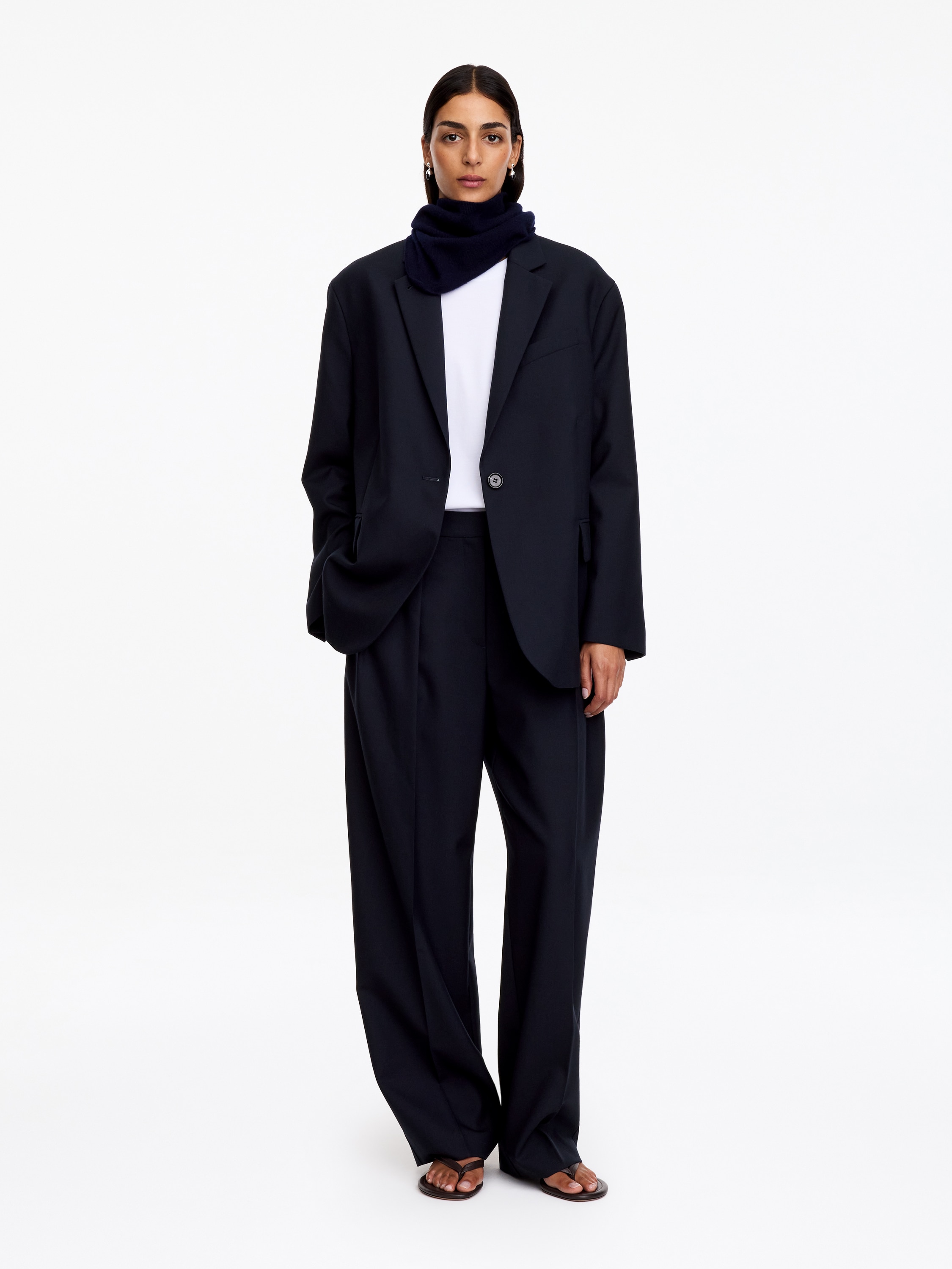 Ein marineblauer, einreihiger Blazer ist von vorne zu sehen und zeigt eine lÃ¤ssige Silhouette mit markanten Schultern und fallendem Revers. Die Jacke verfÃ¼gt Ã¼ber einen Ein-Knopf-Verschluss, eine Brustleistentasche und zwei gerÃ¤umige Pattentaschen.