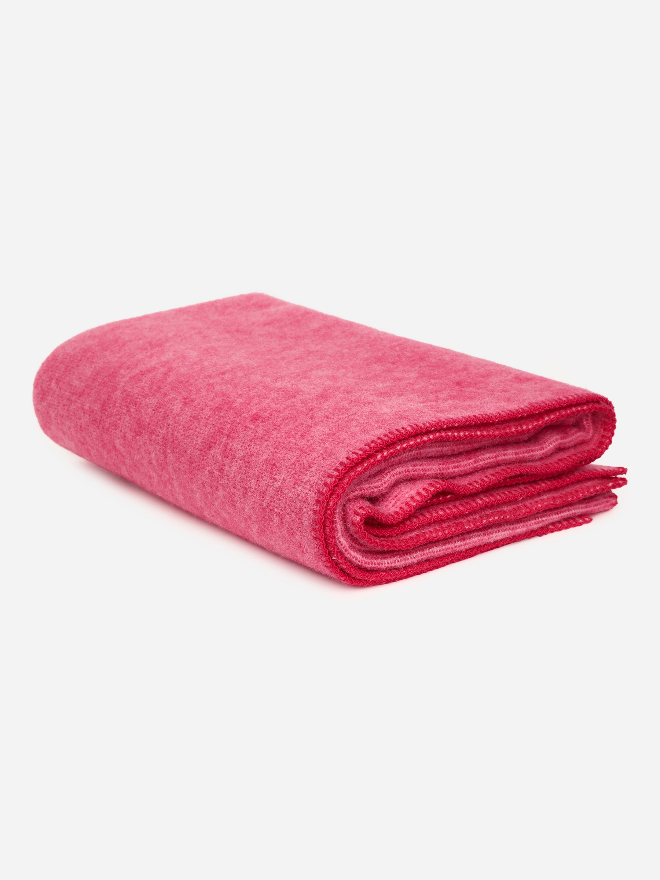 View larger image: A solid pink wool blanket is neatly folded, showcasing blanket stitching along its visible edges.