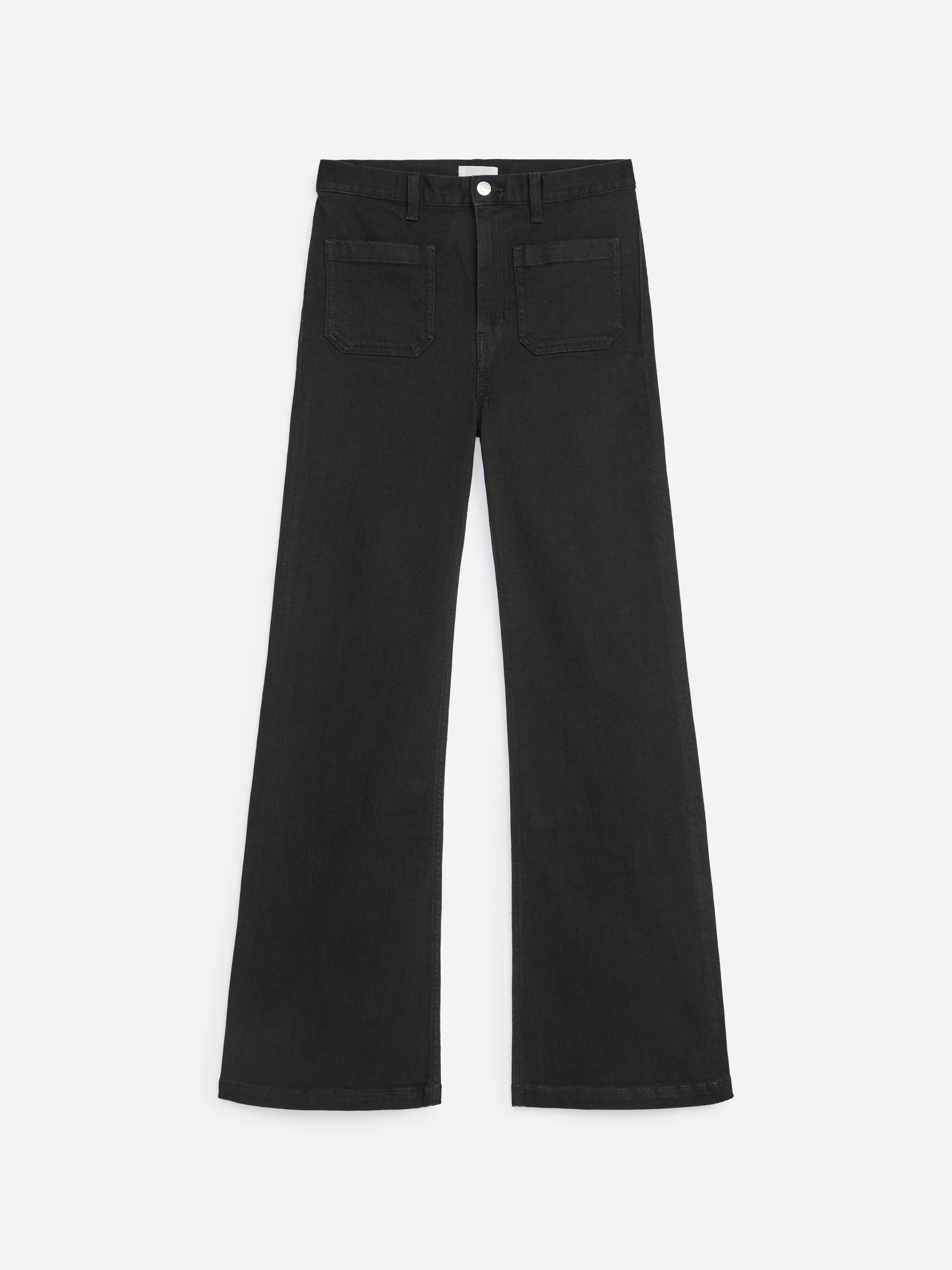 Il modello indossa jeans neri a vita alta con gamba svasata e tasche applicate sul davanti. I jeans sono abbinati a un top bianco a maniche lunghe, infilato nella parte anteriore per mettere in risalto il design a vita alta.