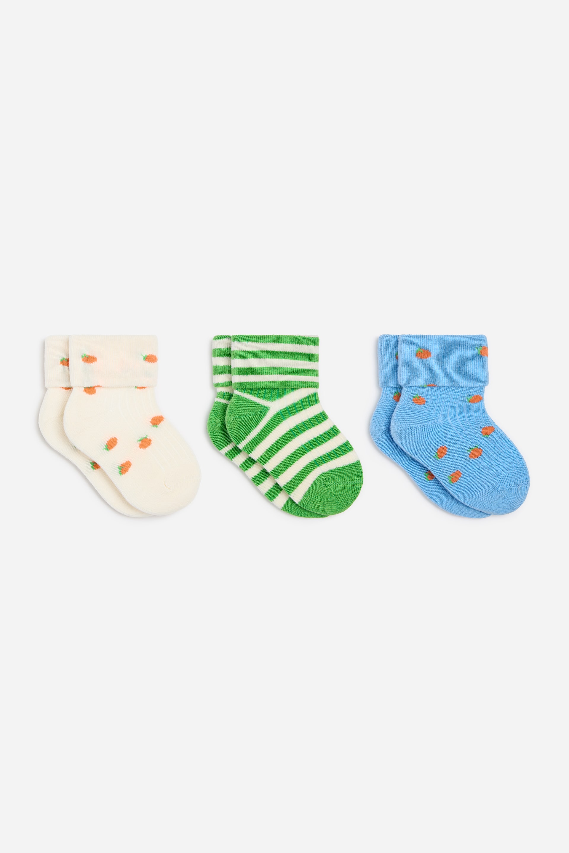 Größeres Bild ansehen: Ein Set aus drei Paaren gerippter Babysocken liegt flach und zeigt ihre Vorderseiten. Ein Paar ist cremefarben mit orangefarbenen Karottenmotiven, ein weiteres ist grün mit weißen horizontalen Streifen, und das dritte ist blau mit orangefarbenen Punktmotiven, wobei jedes Paar über einen gerippten, umgeschlagenen Bund verfügt.