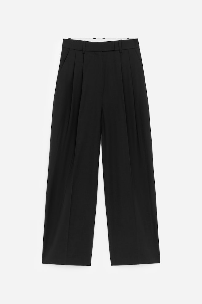 Schwarze Hosen sind von VORNE zu sehen und zeigen eine hohe Taille mit Gürtelschlaufen sowie zwei Falten an jedem Bein. Sie verfügen über weite, gerade Beine und Seitentaschen. - 1