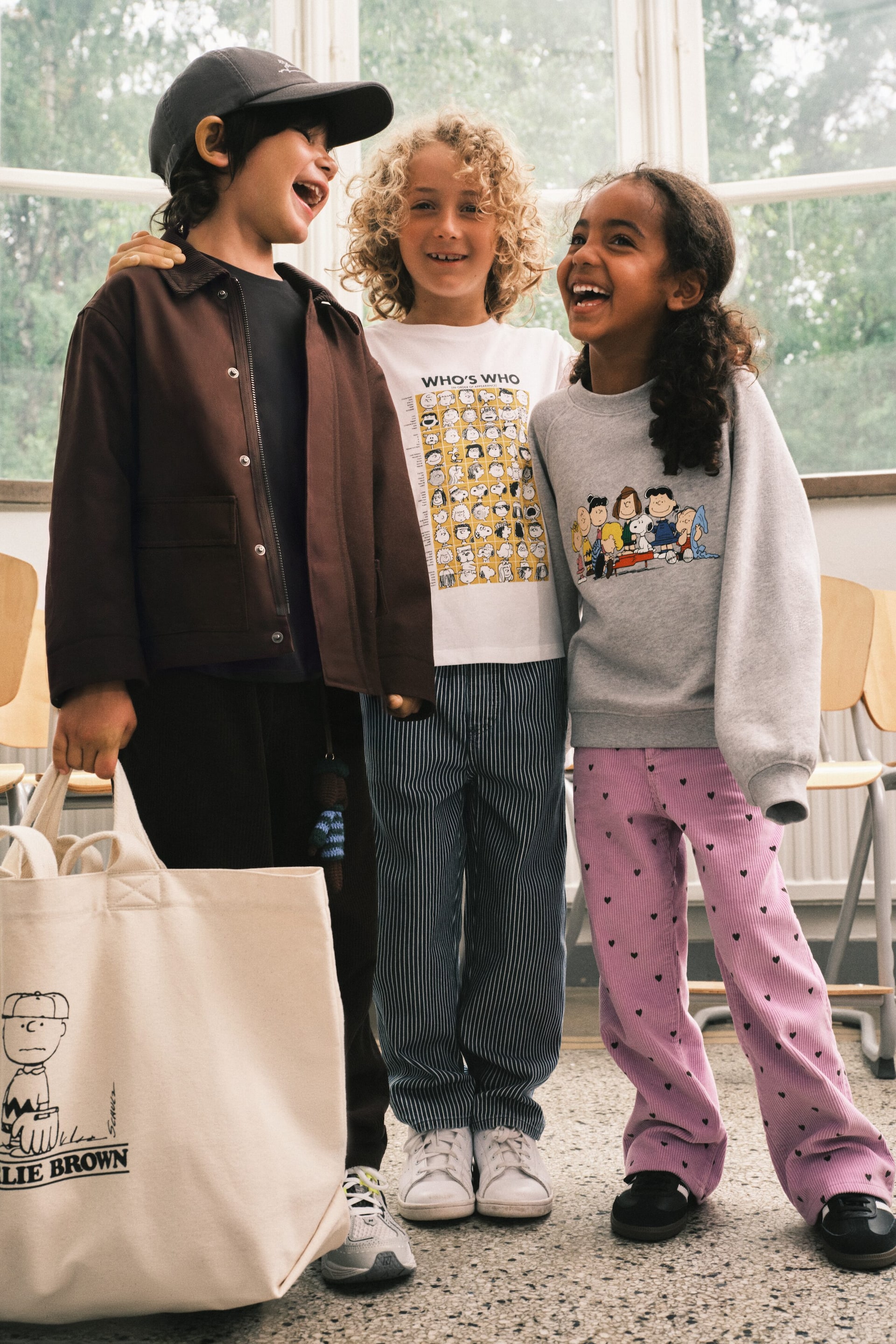 Größeres Bild anzeigen: Eine cremefarbene Canvas-Tote-Bag zeigt einen schwarzen Grafikdruck der Peanuts-Figur Charlie Brown, darunter ist der Schriftzug „Charlie Brown“ aufgedruckt, und sie verfügt über zwei obere Schlaufenhenkel.