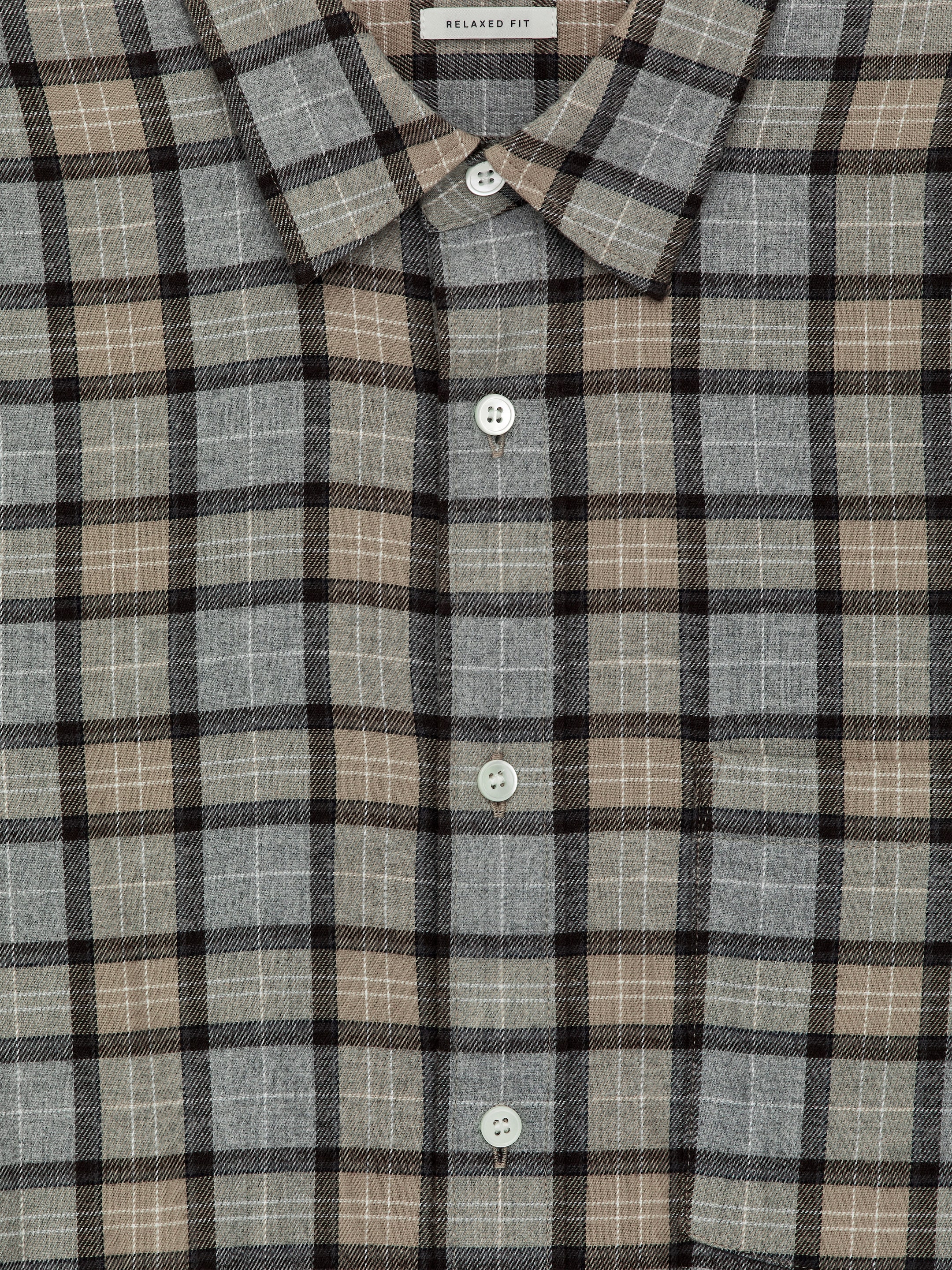 Ver imagen más grande: Una vista FRONTAL de una camisa de franela de algodón muestra un patrón de cuadros en gris, marrón y negro con finas líneas de cuadrícula blancas. Presenta un cuello puntiagudo y una tapeta de botones frontales con botones de nácar blancos, y está diseñada con un ajuste relajado, como lo indica una etiqueta visible.