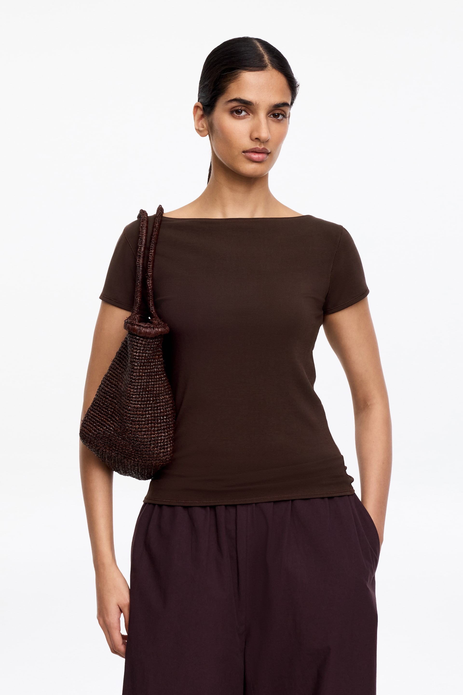 Visa större bild: En mörkbrun t-shirt med båturringning och korta ärmar. Den har en figurnära silhuett.