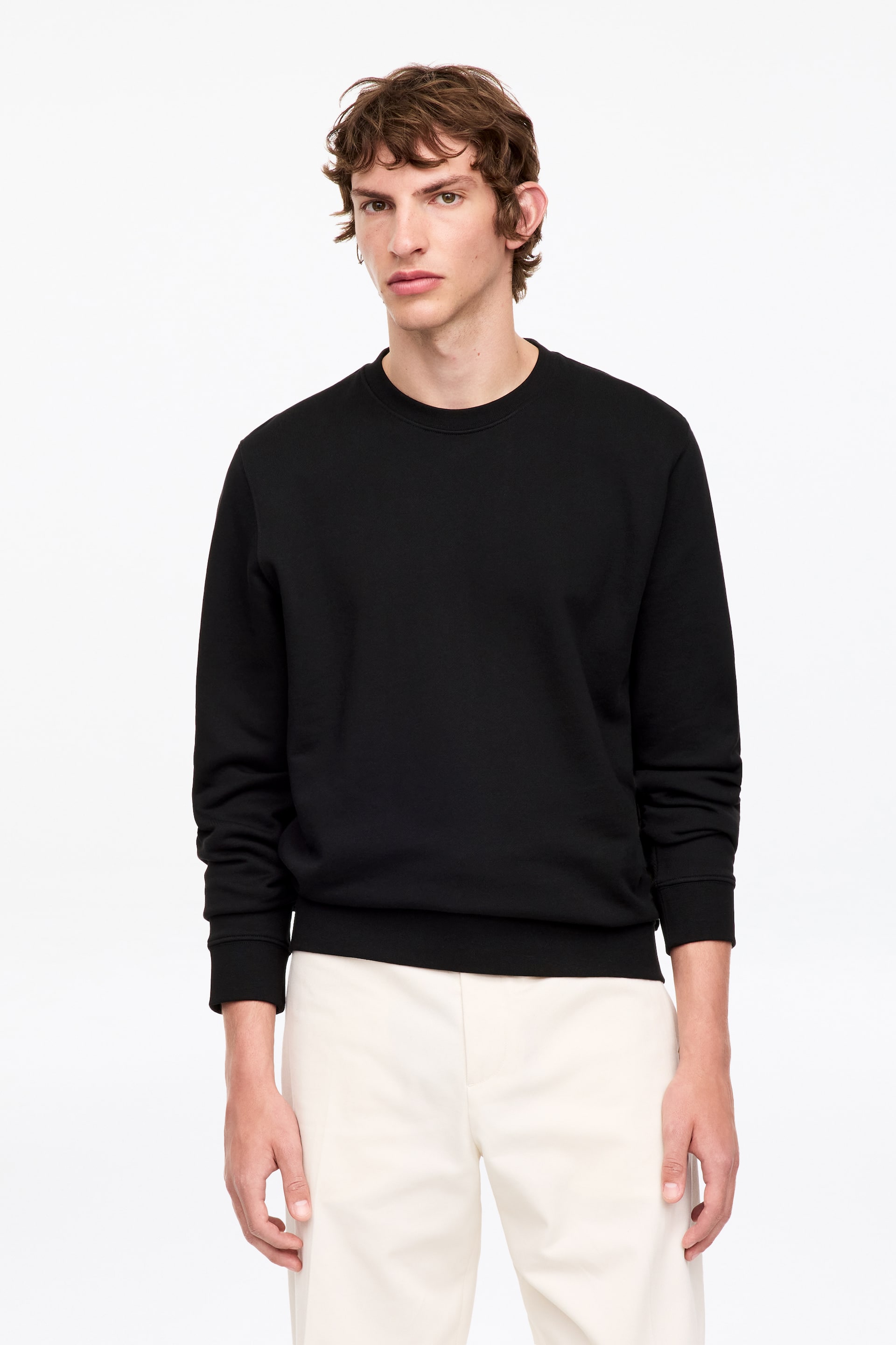 Grösseres Bild ansehen: Das schwarze Sweatshirt mit Rundhalsausschnitt ist nach vorne gerichtet und verfügt über lange Ärmel mit gerippten Bündchen und einem gerippten Saum. Es zeigt einen glatten Stoff und eine lockere Passform.