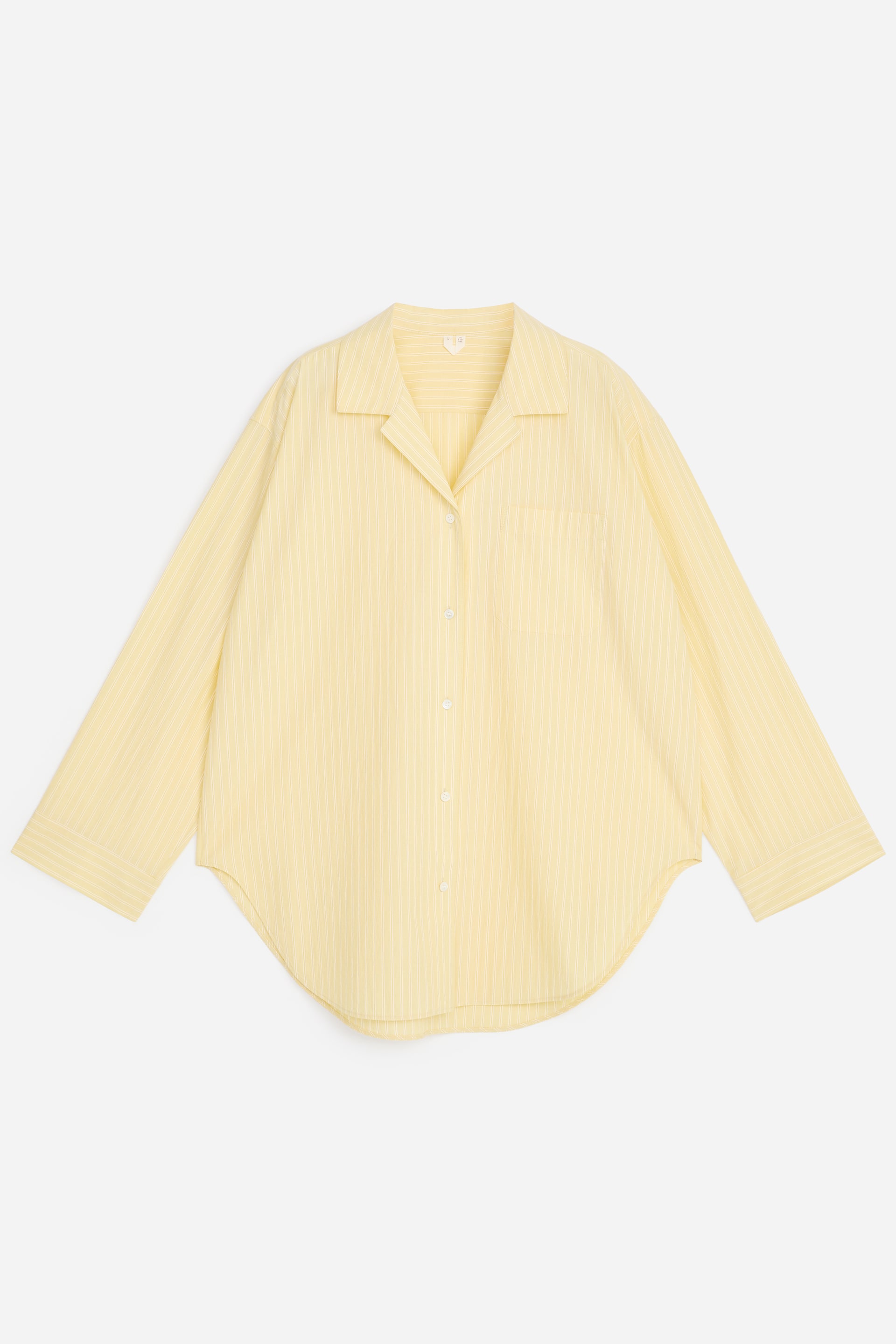 Visualizza immagine più grande: Una camicia gialla oversize con sottili righe verticali bianche è esposta frontalmente, distesa in piano. Presenta un colletto a revers, una chiusura frontale con bottoni, maniche lunghe, una tasca singola sul petto a sinistra e un orlo arrotondato.