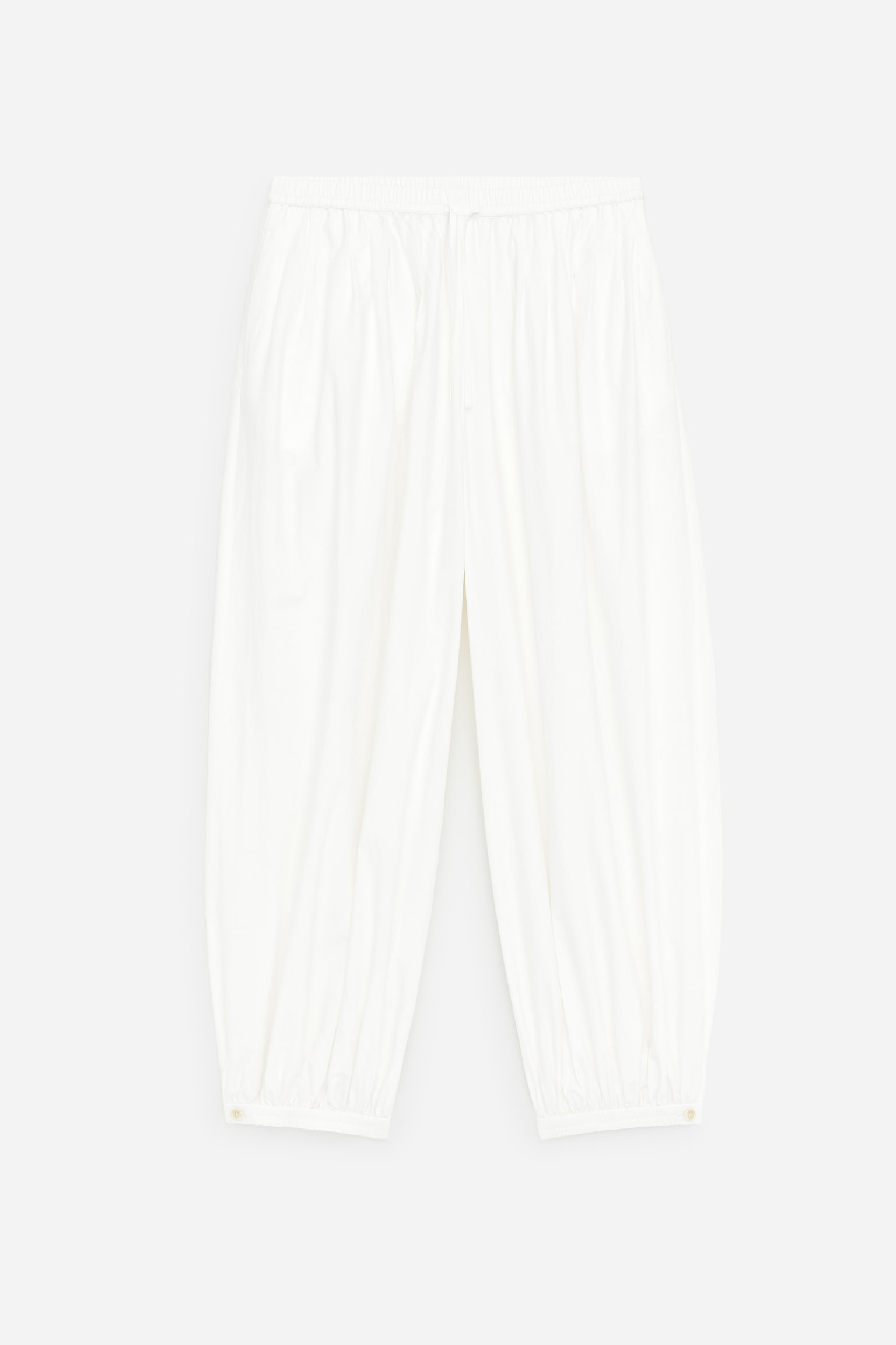 Weiße, knusprige Baumwoll-Popeline-Hose, wie FRONT, präsentiert eine Ballonsilhouette, mit einem elastischen Bund und einer feinen Kordel, weichen Falten, die in Bundfalten um die Taille übergehen, und gerafften Bündchen, die jeweils mit einem kleinen Knopf versehen sind. - 1