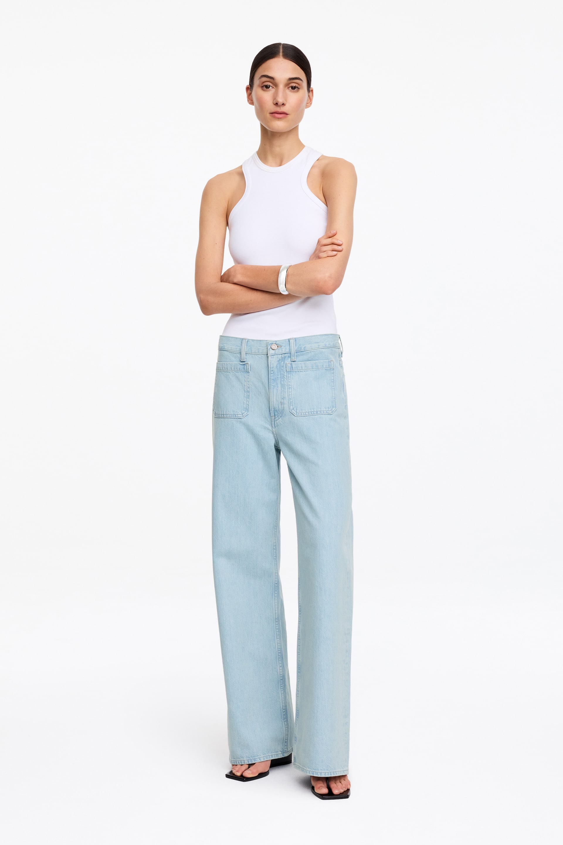 Se større billede: Højtaljede, lyse denimjeans med en slank pasform og udsvingende ben bæres af modellen. Jeansene har synlige lappelommer foran.