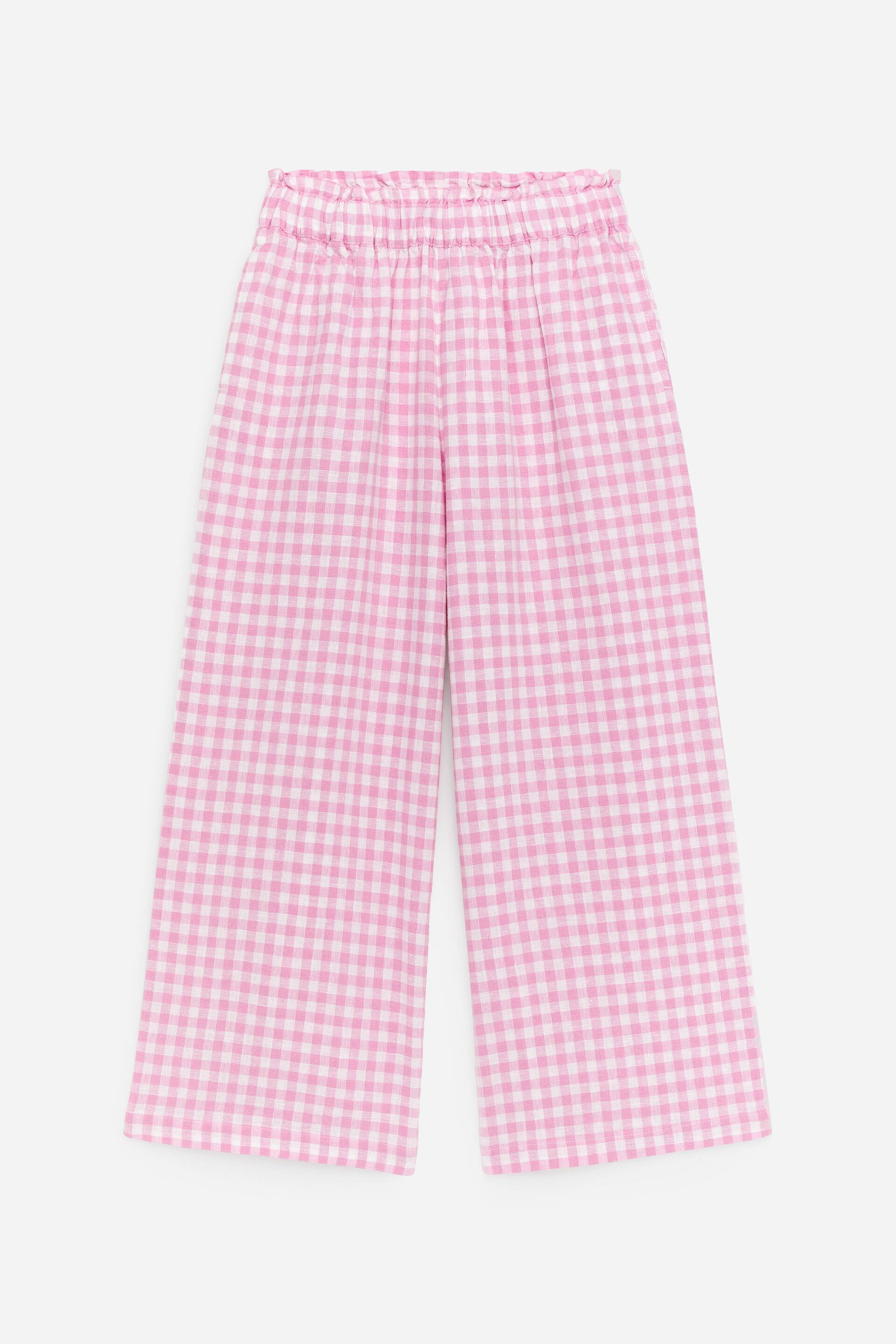 Näytä suurempi kuva: Vaaleanpunaiset ja valkoiset gingham-housut, joissa on röyhelöinen paperipussivyötärö, rennot leveät lahkeet ja hienovaraiset sivutaskut, esitetään edestäpäin.