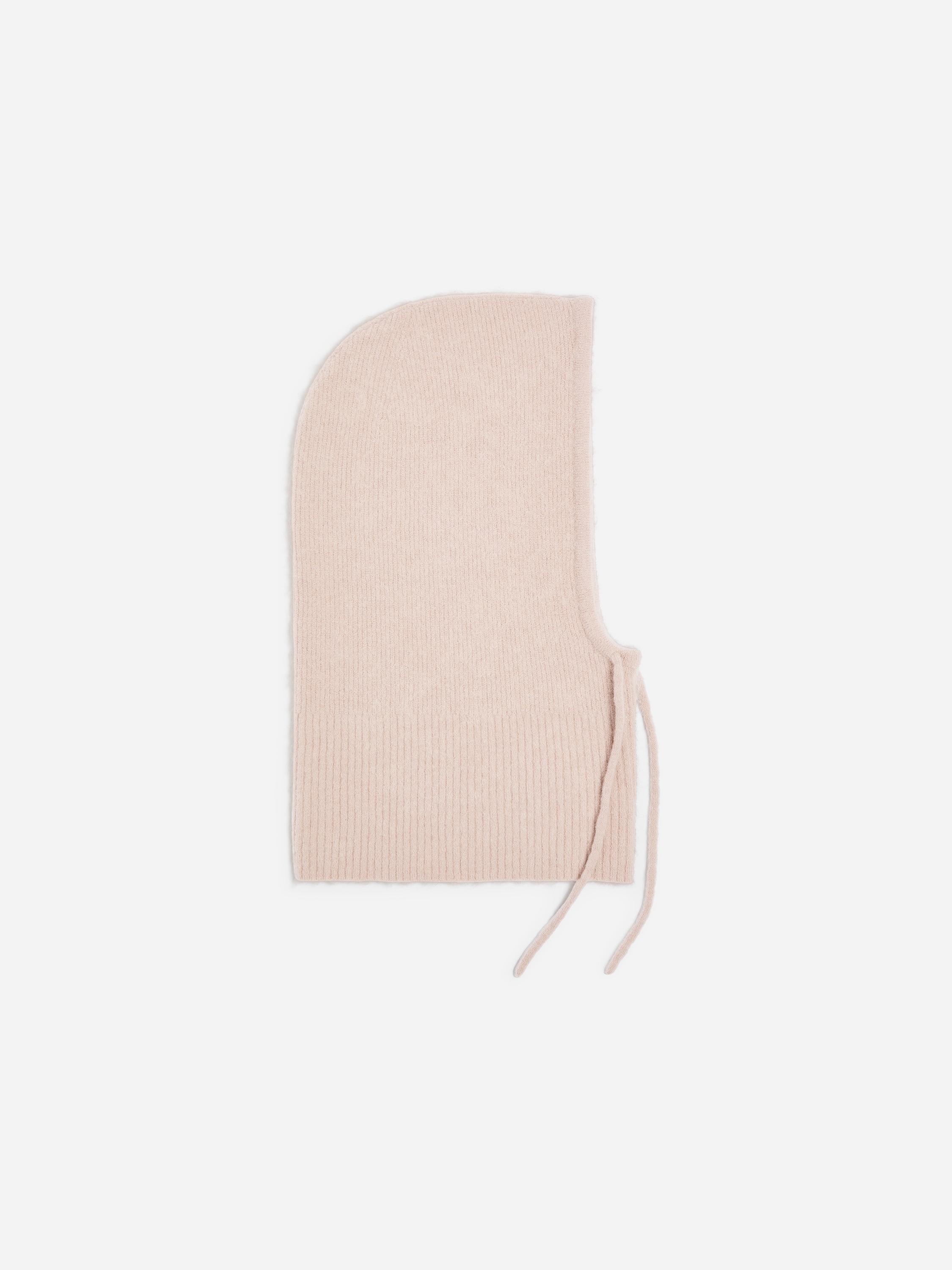 Un capuchon en maille texturée rose clair est porté par le mannequin, encadrant son visage et son cou. Le capuchon est porté sous une veste noire dotée d’un col montant et matelassé.