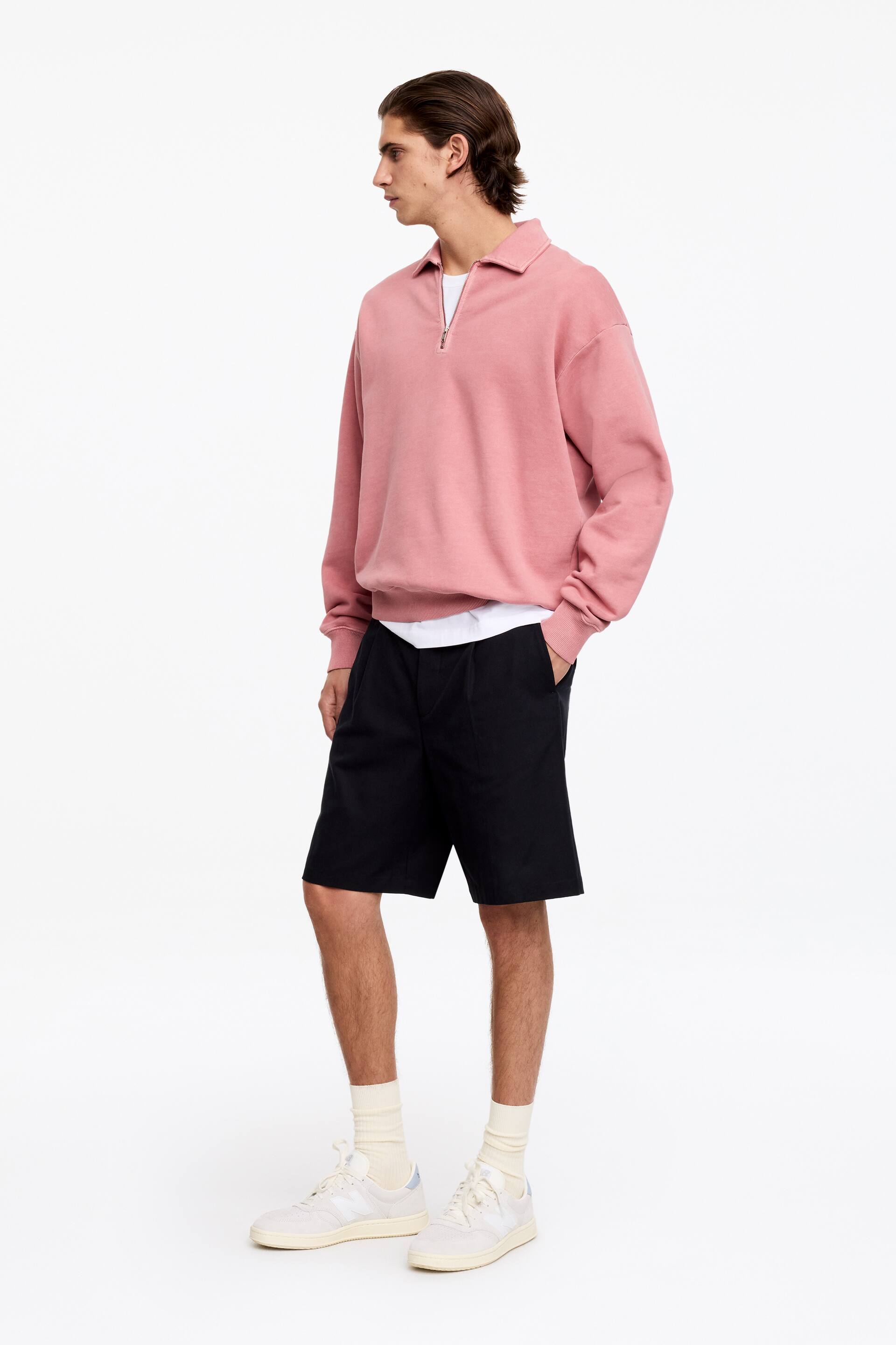 Zobrazit větší obrázek: Růžová mikina se čtvrtým zipem je prezentována z bočního úhlu, s polokošilovým límečkem a stříbrným zipem. Je navržena s dlouhými rukávy, žebrovanými manžetami a žebrovaným lemem, pod níž je viditelná bílá trička.