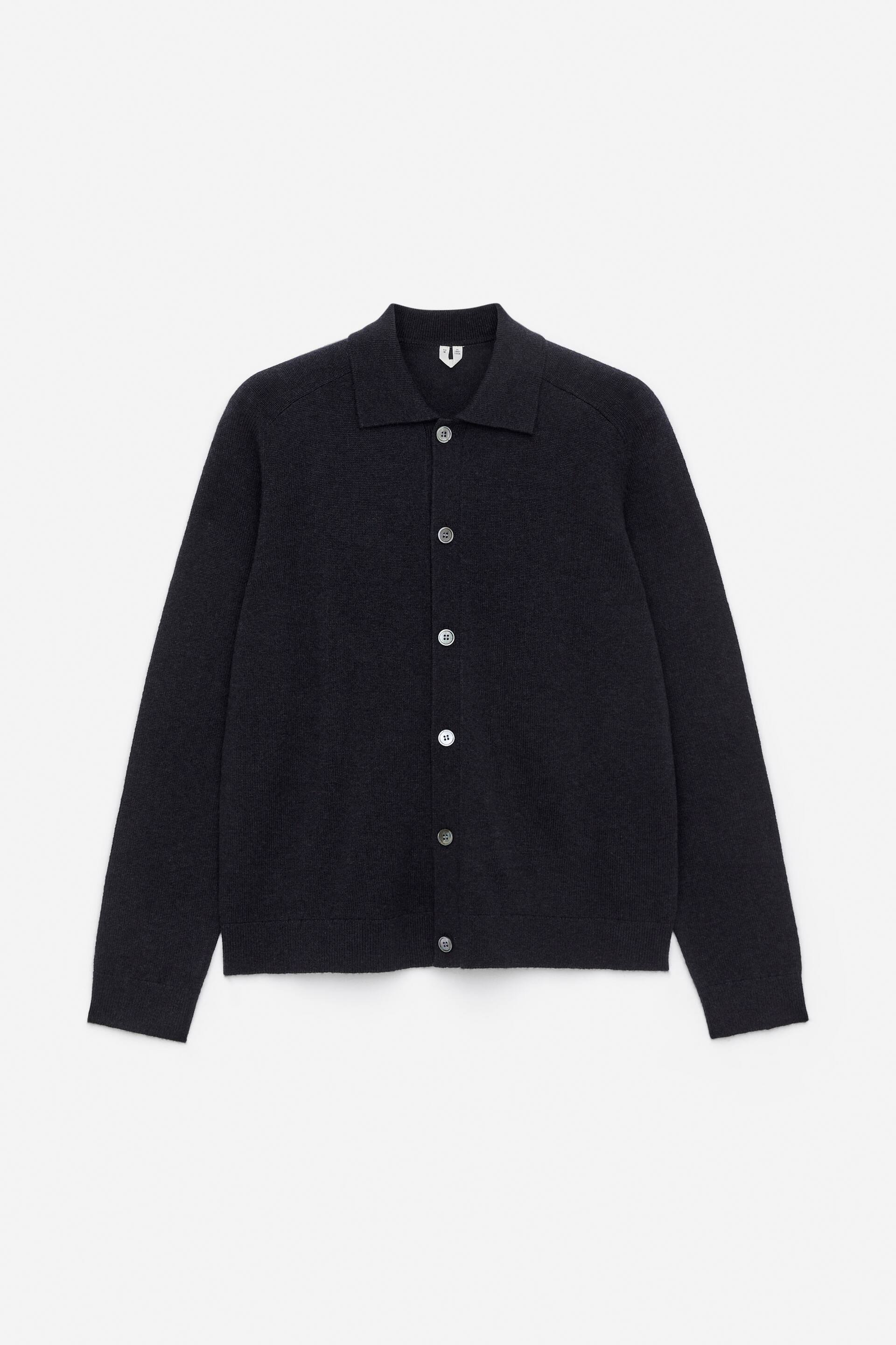 Vis større bilde: En mørkfarget cardigan vises fra FRONTEN, med en glattstrikket kropp og en fullnålsstrikket krage, stolpe, mansjetter og kant. Den er stilisert med en vanlig passform og viser lyse knapper nedover fronten.