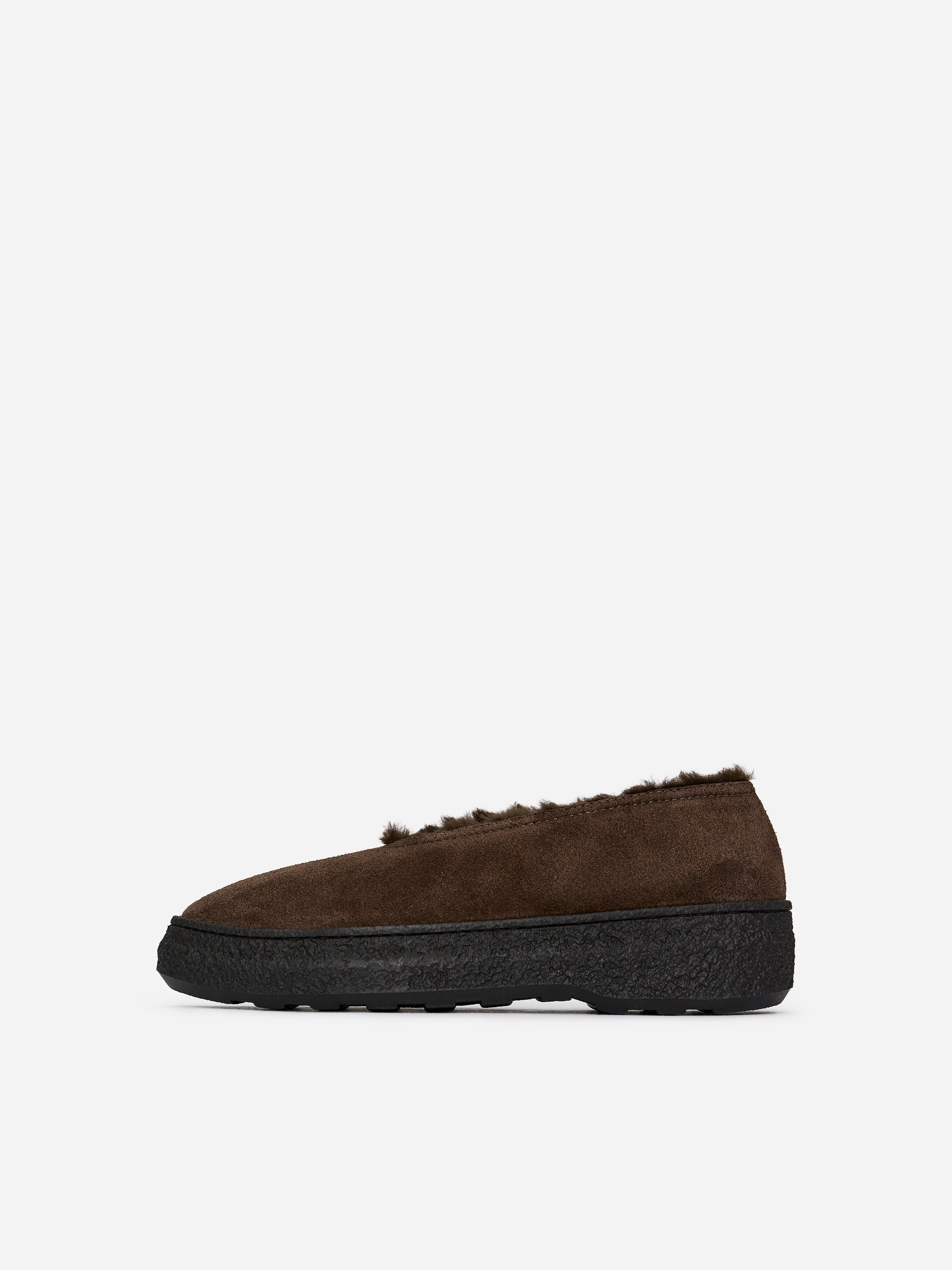 Agrandir l'image: Une chaussure en daim marron exhibe un profil latéral. Elle présente une semelle épaisse noire avec une surface texturée, et une doublure en fourrure brun foncé est visible le long de son bord supérieur.