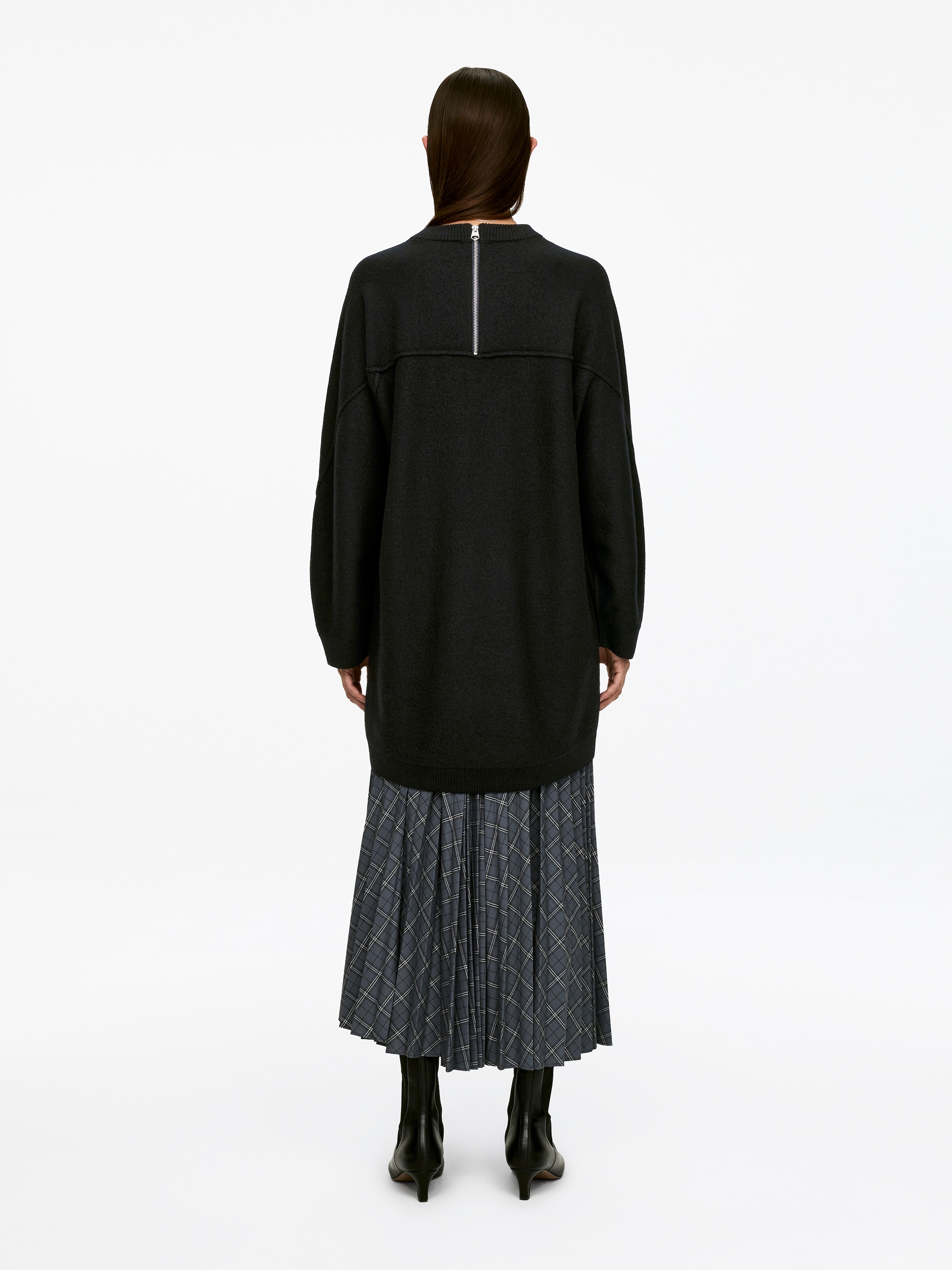 Visualizza immagine più grande: Un abito mini grigio scuro a vestibilità ampia, realizzato in lana bollita, viene indossato dalla modella. Presenta maniche lunghe e una mezza zip color argento sul retro ed è abbinato a una gonna midi a pieghe a quadri.