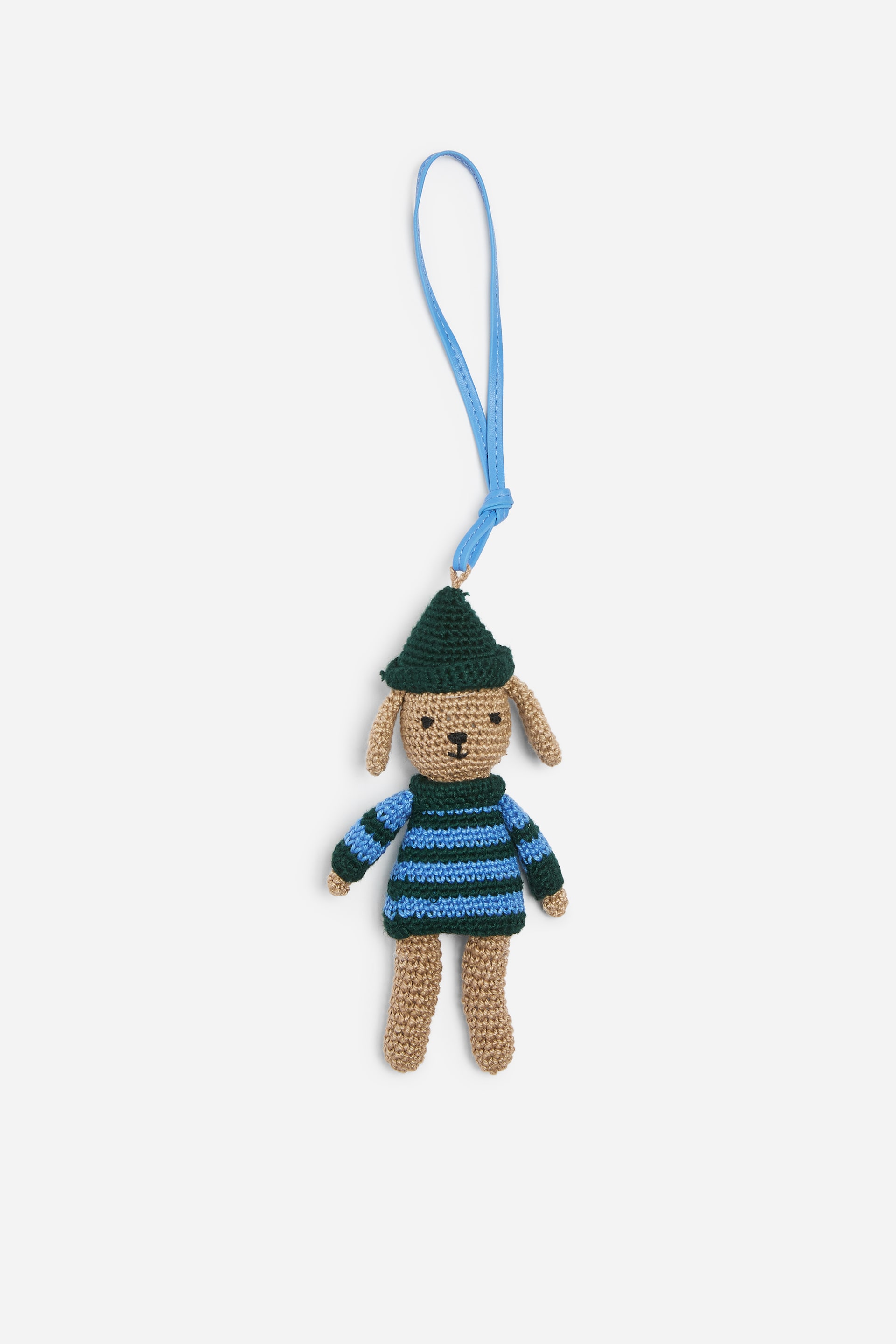 Ver imagen más grande: Un colgante de bolso de ganchillo, visto de frente, que representa a un pequeño animal similar a un perro, cuelga de una lazada de color azul brillante. La figura tejida de color marrón claro lleva un sombrero puntiagudo verde oscuro y un jersey a rayas azules y verde oscuro.