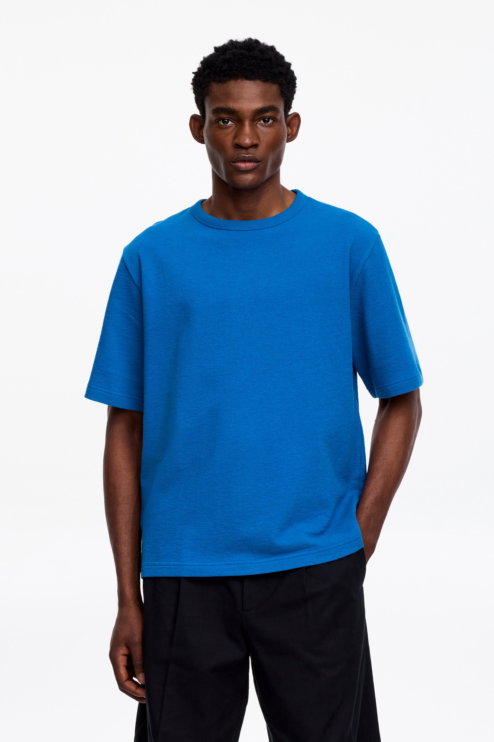Grotere afbeelding bekijken: Het blauwe T-shirt heeft een ronde hals en korte mouwen. Het is voorzien van een gestructureerde stof, een ontspannen pasvorm en een rechte zoom.