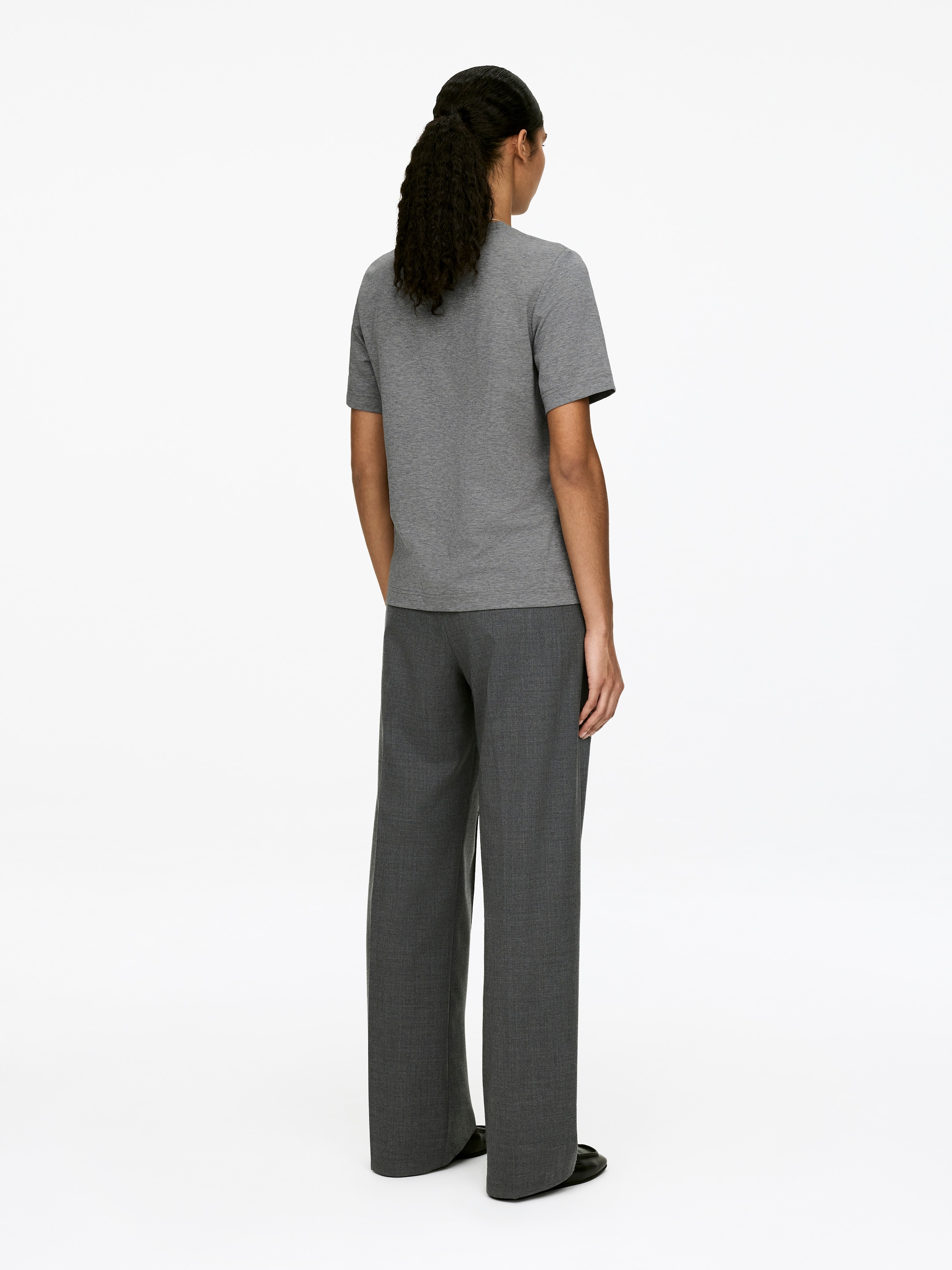 View larger image: A grey T-shirt is being worn by the model, who is standing facing away from the viewer. The T-shirt features short sleeves and a straight hem, presenting a regular fit on the body.