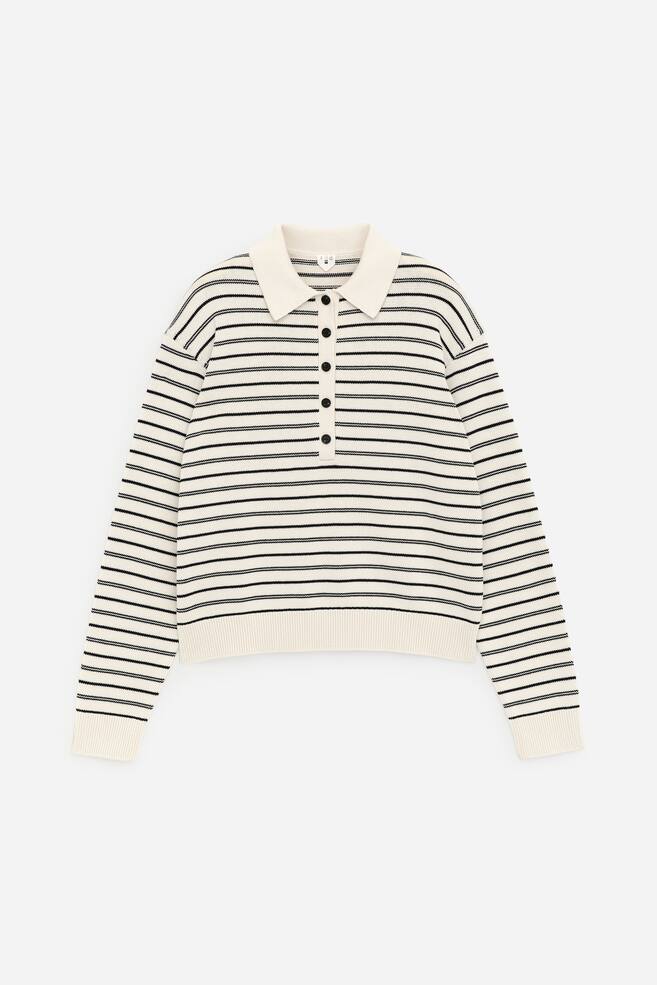 Un jersey de rayas crema y negro se presenta en su vista FRONTAL, con un cuello polo y una tapeta de cinco botones. Está diseñado con mangas largas, puños acanalados y un dobladillo acanalado. - 1