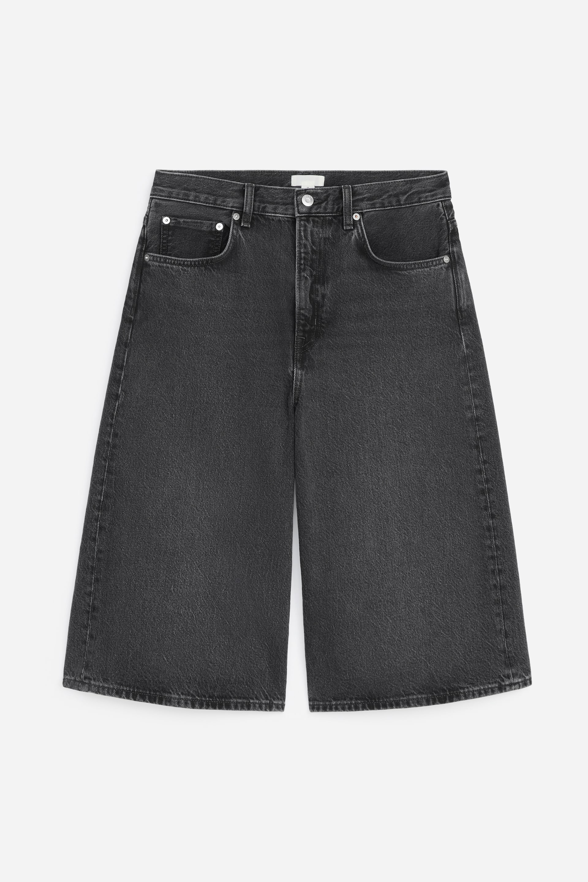 Ver imagen más grande: Los pantalones cortos de mezclilla gris oscuro presentan una silueta relajada de longitud a la rodilla vista desde el frente. Cuentan con dos bolsillos delanteros tipo "scoop", un bolsillo para monedas, una bragueta con cremallera y un cierre de botón de remache en la cintura.