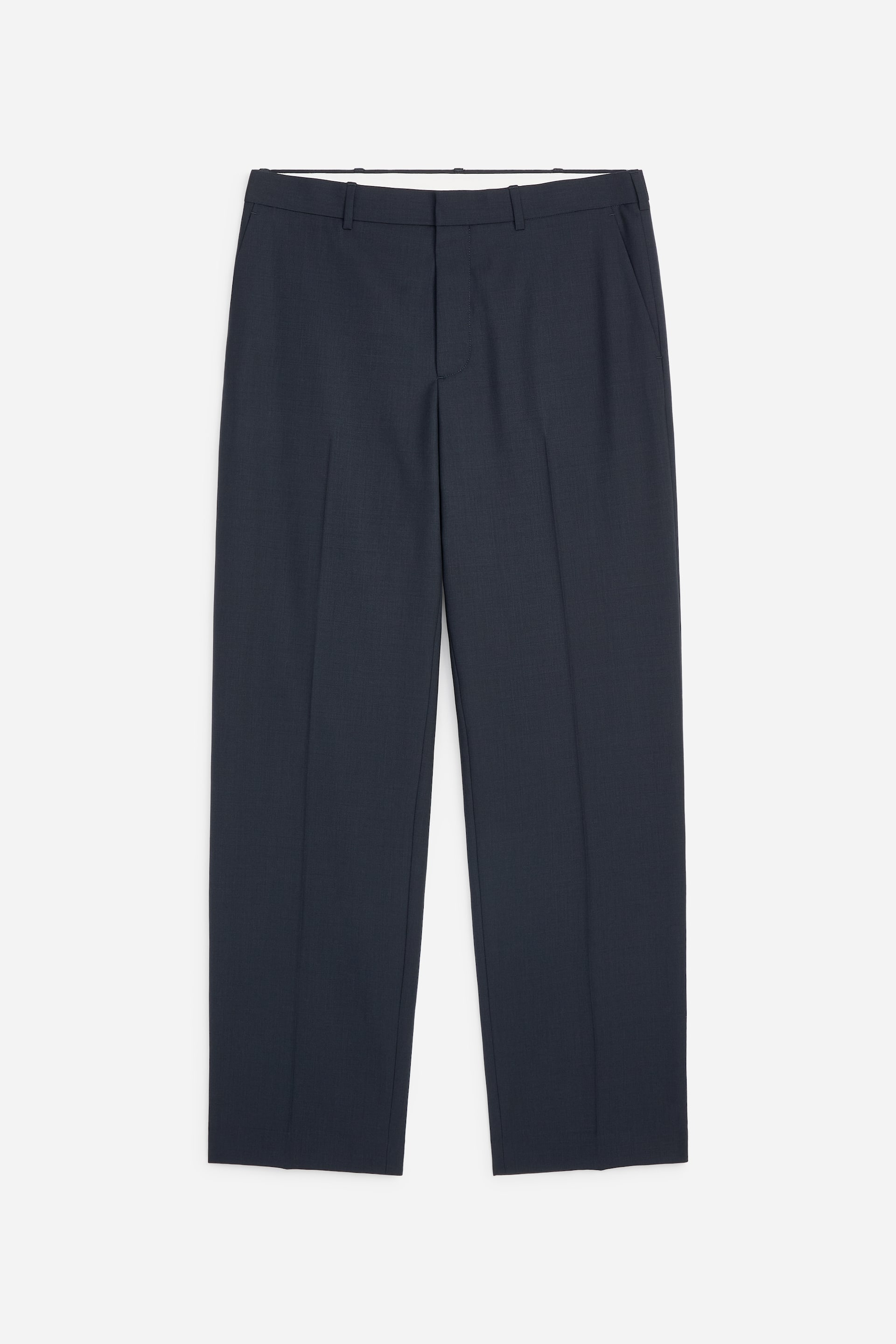 Grotere afbeelding bekijken: Donkerblauwe broek met een platte voorkant, een ritssluiting en een enkele knoopsluiting. Ze zijn voorzien van riemlussen, schuine steekzakken aan de zijkant en geperste vouwen die over het midden van elke rechte pijp lopen.