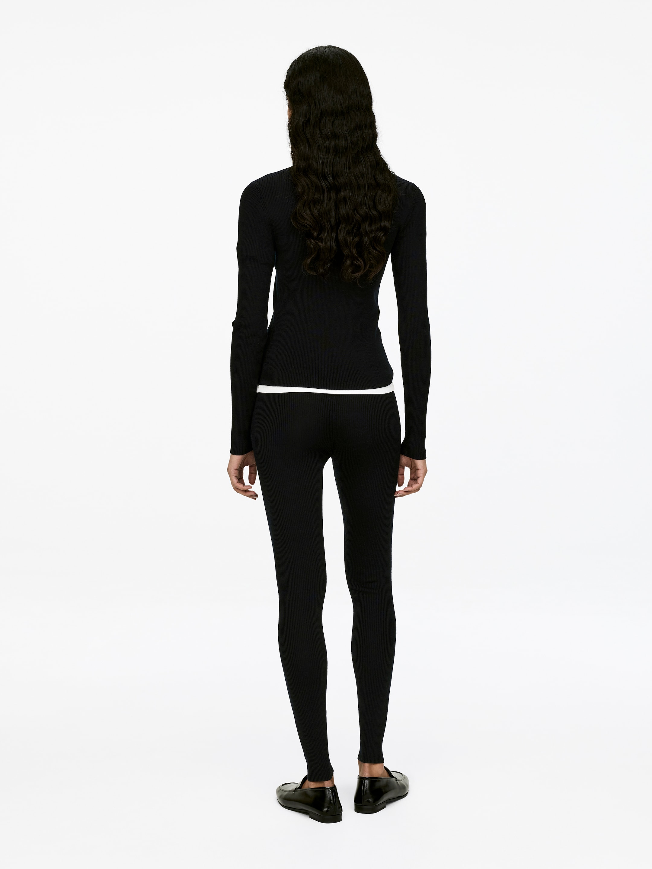 Se større billede: Sorte, ribstrikkede leggings bæres af modellen, set bagfra. De tætsiddende leggings har et højtaljet design og en synlig ribbet struktur langs benene.