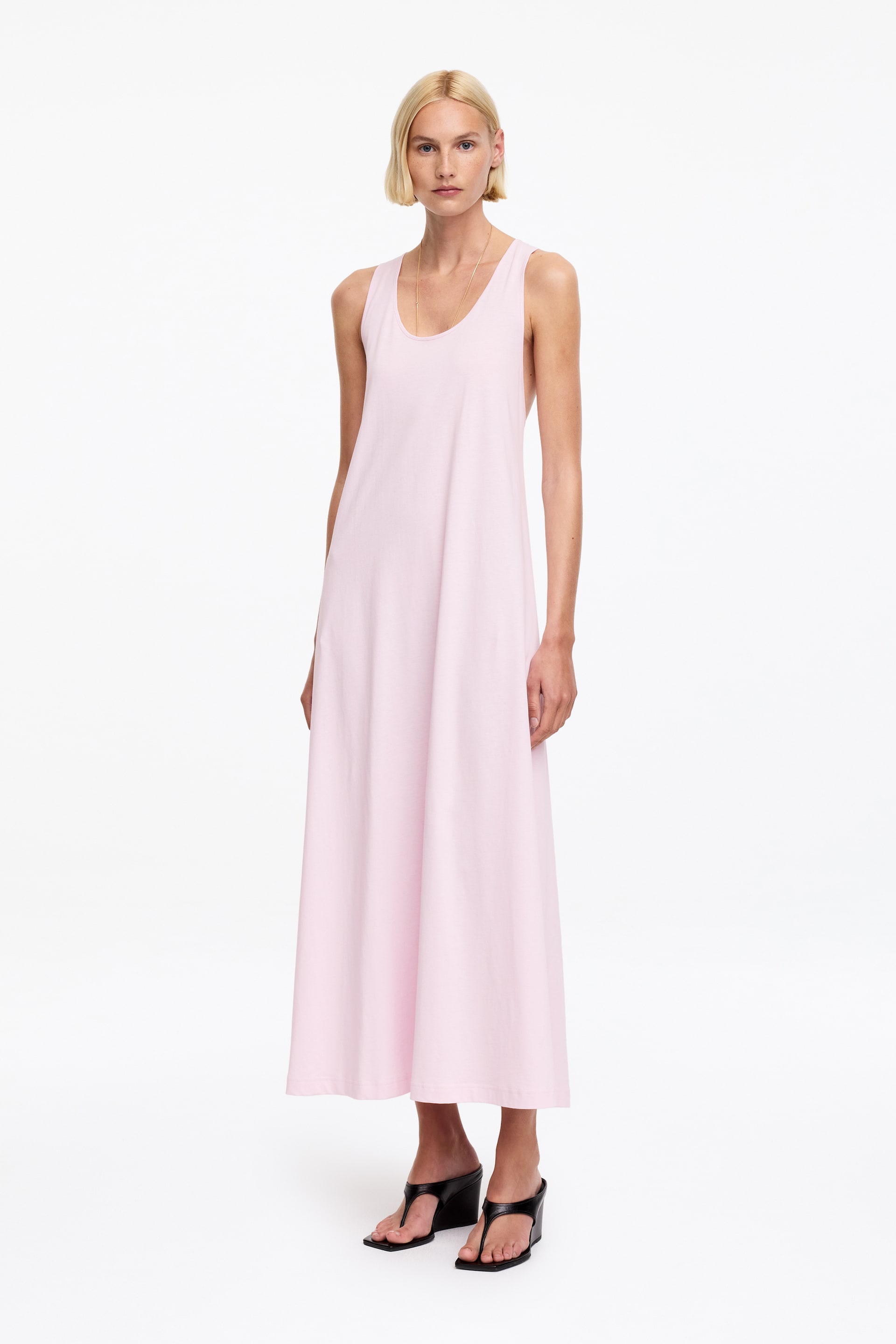 Ver imagen más grande: Un vestido maxi rosa claro se muestra desde el frente, con un escote redondo y tirantes anchos sin mangas. El vestido cae en una silueta suelta en forma de A, extendiéndose hasta la longitud del tobillo.