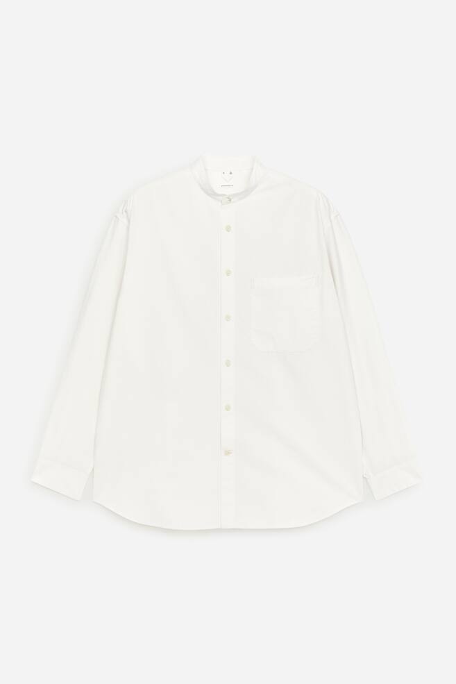 A white cotton poplin shirt is showcased at the FRONT, featuring a relaxed fit, a band collar, and a single chest pocket on its left side. Mother of pearl buttons fasten the front placket. - 1