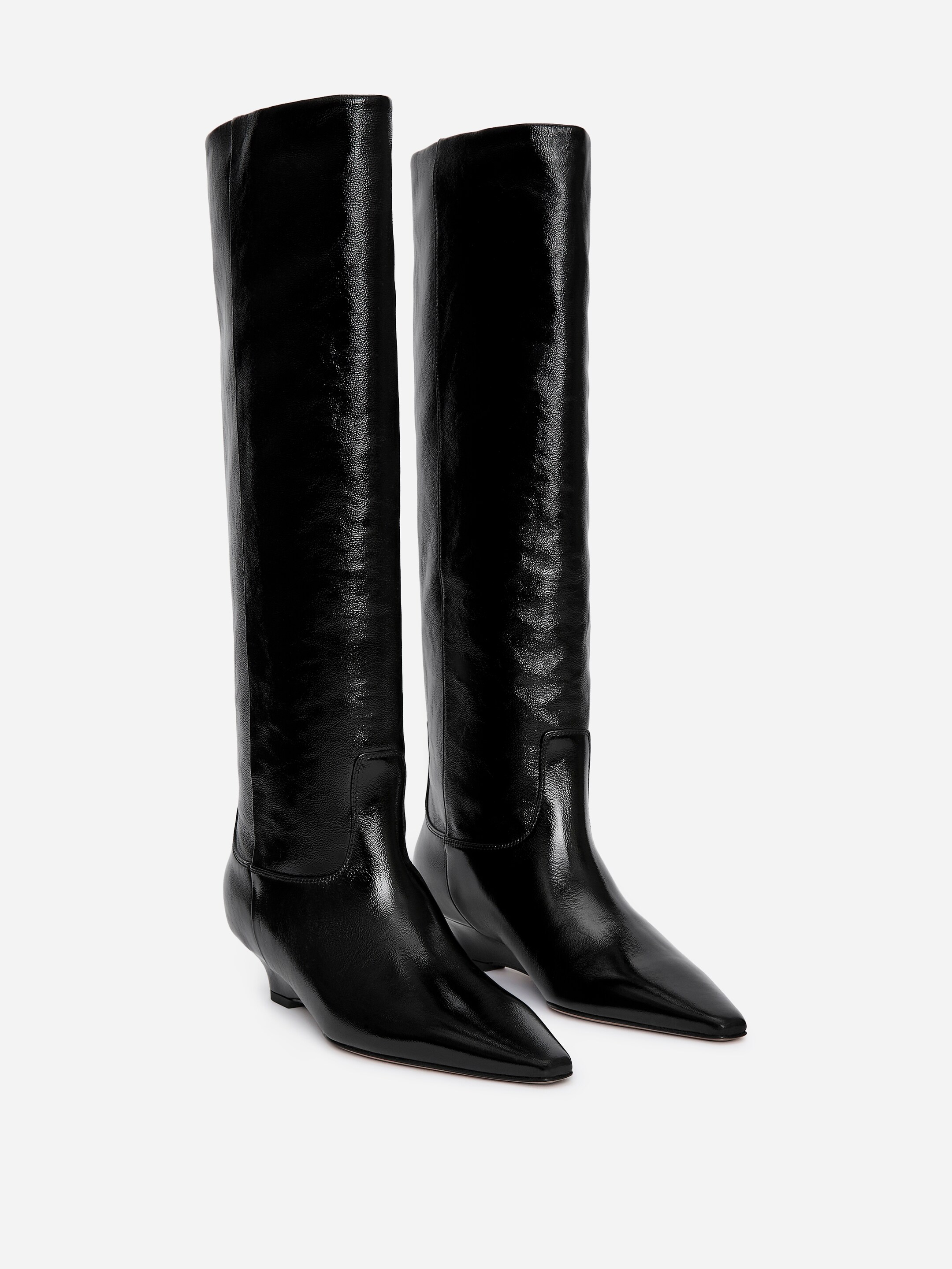 Agrandir l'image: Une paire de bottes noires à haute brillance est posée, avec des tiges hautes légèrement froissées, des bouts pointus et de petits talons aiguilles.