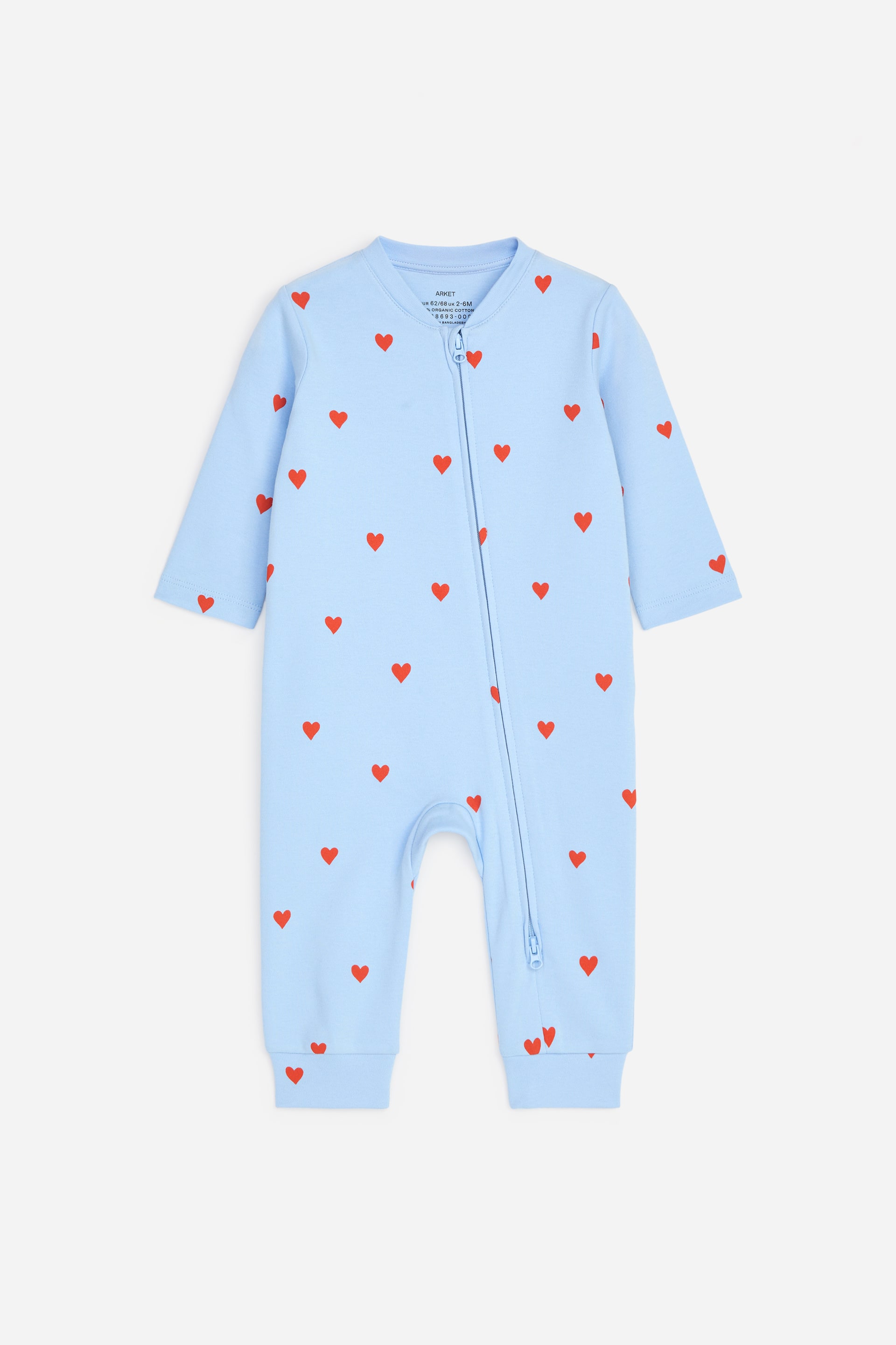 Agrandir l'image: Un pyjama bleu clair en jersey doux avec un imprimé intégral de cœurs rouges. Il est doté d'une fermeture éclair diagonale à double sens s'étendant de l'encolure à la cheville gauche.