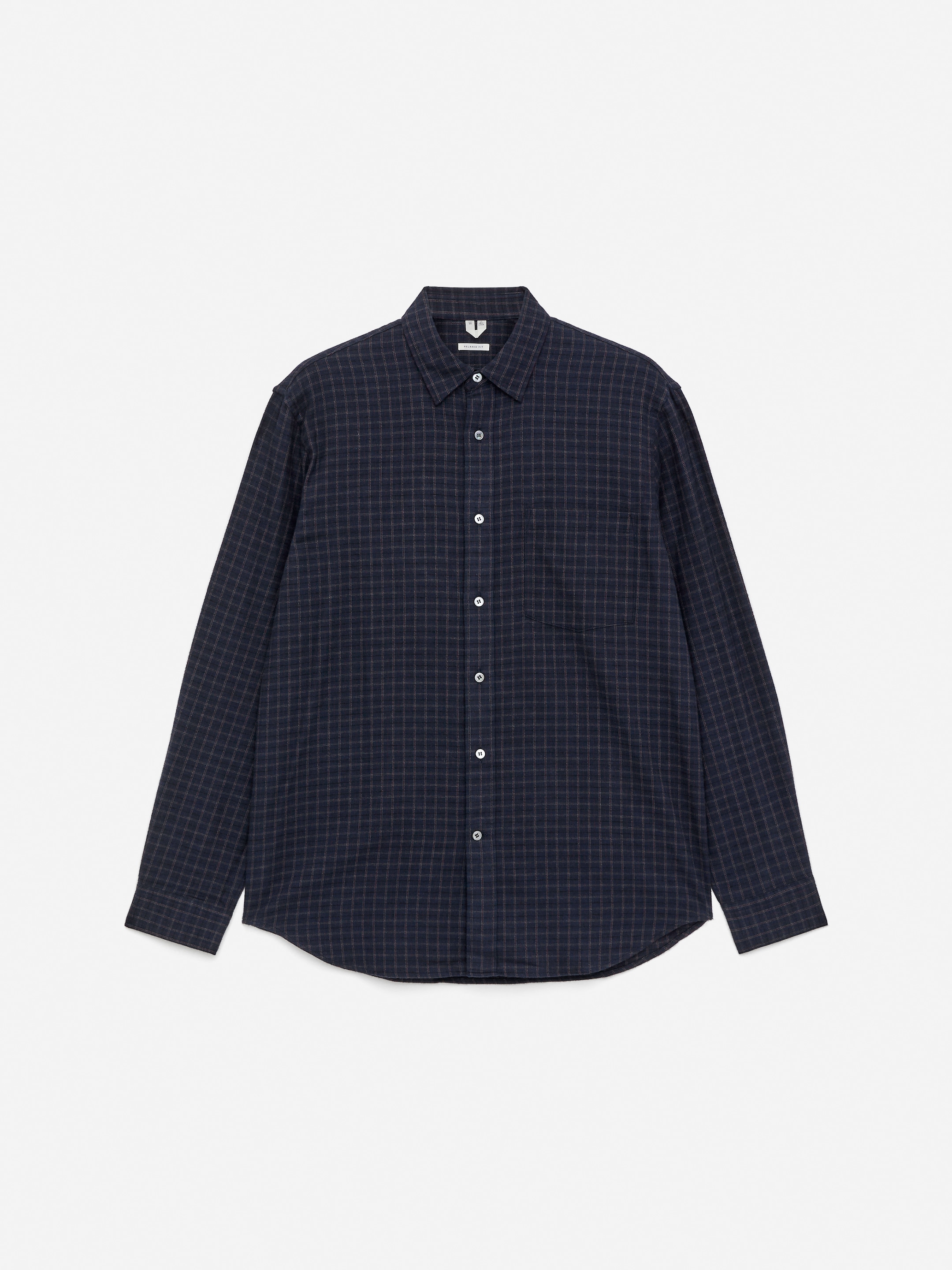 Visualizza immagine più grande: Una camicia di flanella di cotone viene presentata dal davanti, caratterizzata da un motivo a quadri blu scuro. È progettata con una vestibilità rilassata, una singola tasca sul petto e bottoni in madreperla.