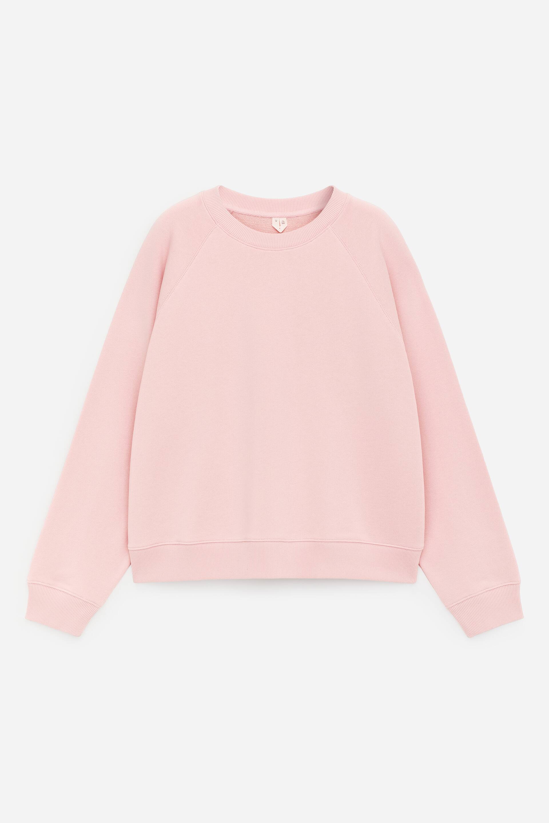 Visa större bild: En rosa crewneck-sweatshirt visas FRAMIFRÅN, lagd plant, med ribbad halsringning, raglanärmar, ribbade muddar och ribbad nederkant.