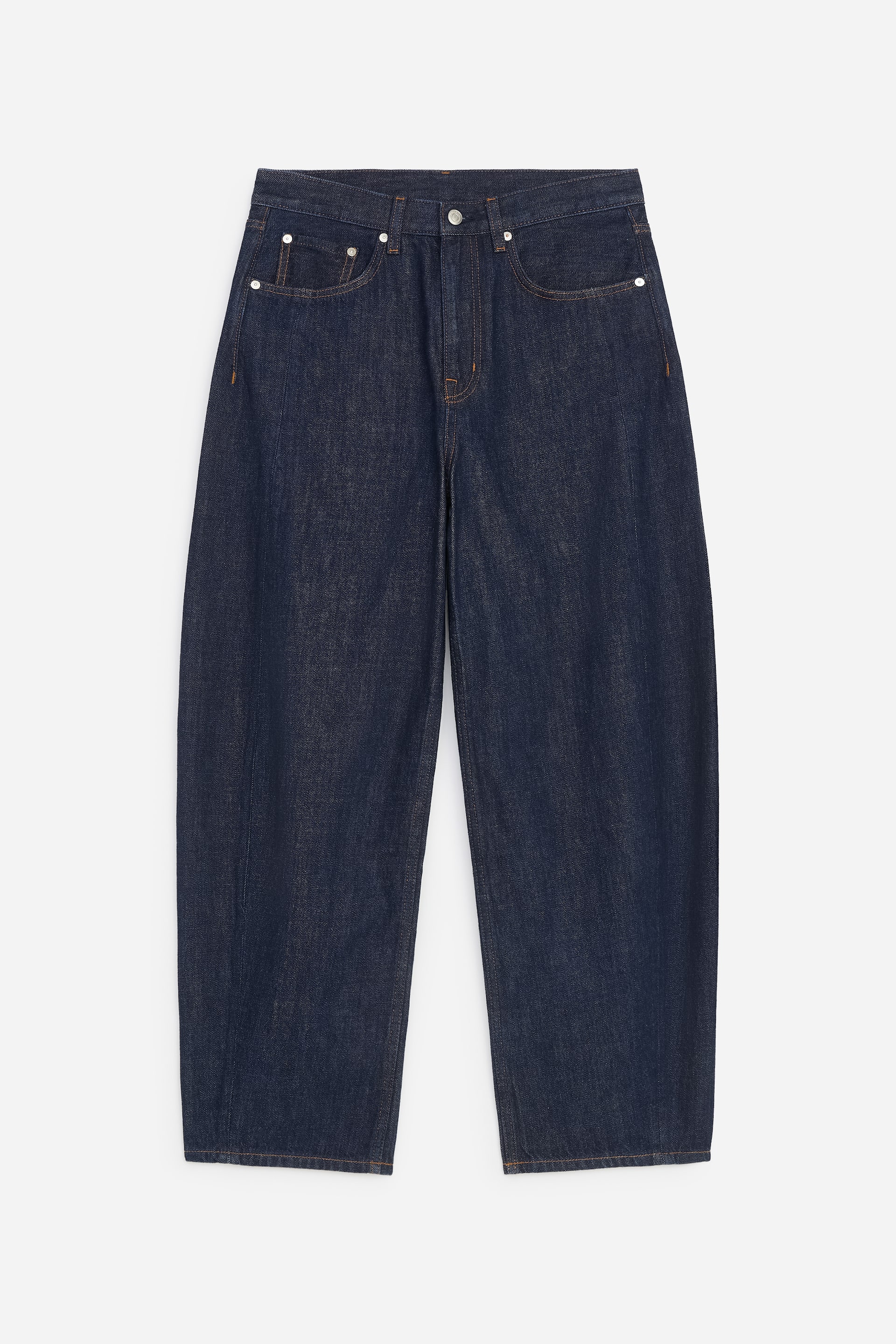 Ver imagem maior: Um par de jeans de ganga índigo em lavagem escura está virado para a frente, destacando uma cintura de cintura média e um corte descontraído com pernas esculpidas e cropped. Os jeans apresentam o clássico estilo de cinco bolsos com pespontos em contraste e fecho de botão em tom prateado.