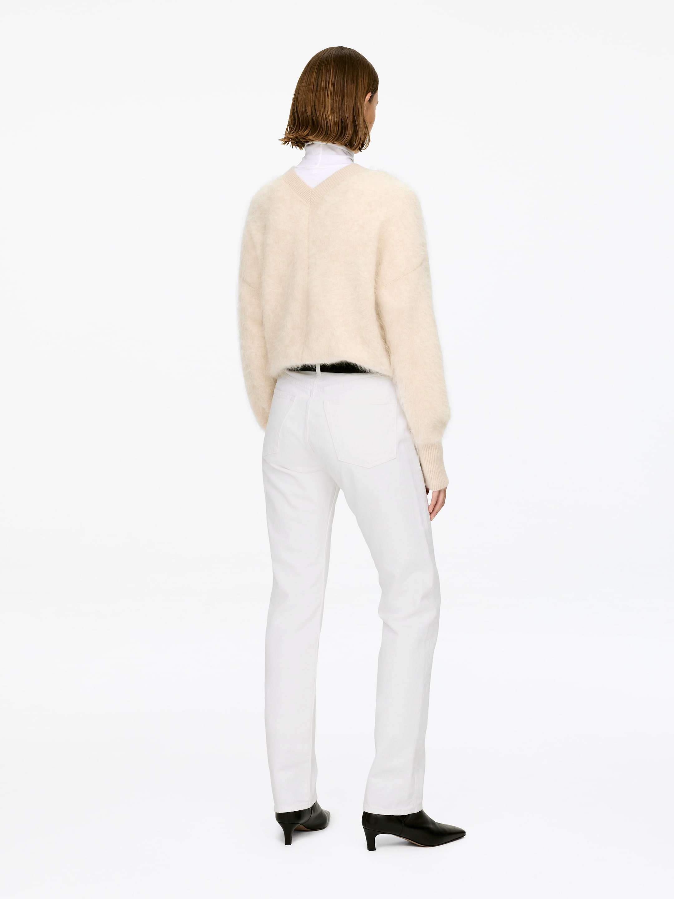 Ver imagem maior: Jeans brancas SNOW, feitas de ganga sem elasticidade, estão a ser usadas pela modelo. Os jeans têm uma cintura de altura média, um corte justo e pernas retas, e estão a ser conjugados com botas pretas e por baixo de uma camisola de cor clara.