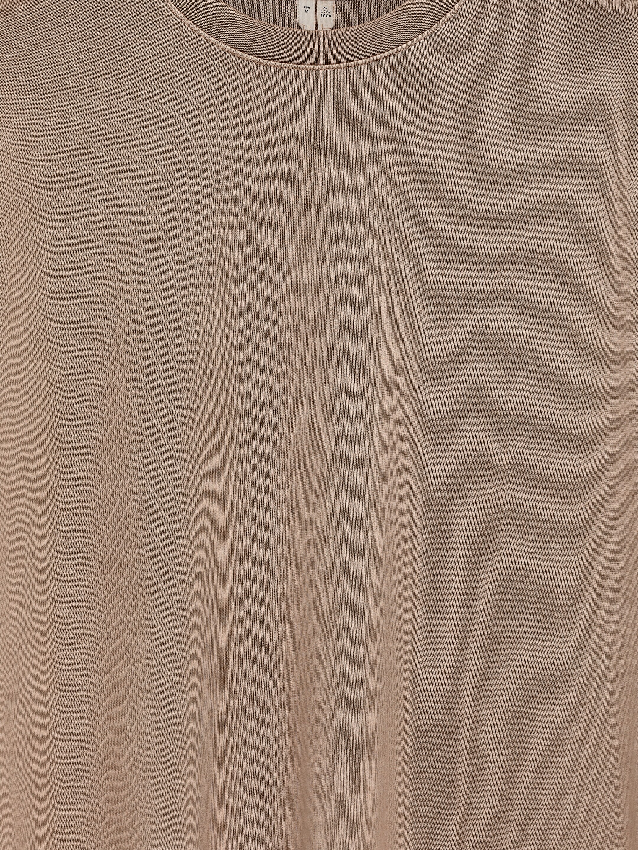 Grösseres Bild ansehen: Ein langärmliges T-Shirt zeigt seine Vorderansicht. Es ist aus einem melierten hellbraunen Baumwollstoff gefertigt und verfügt über einen klassischen Rundhalsausschnitt mit geripptem Besatz. Produktetiketten sind im Inneren des Halsausschnitts sichtbar.