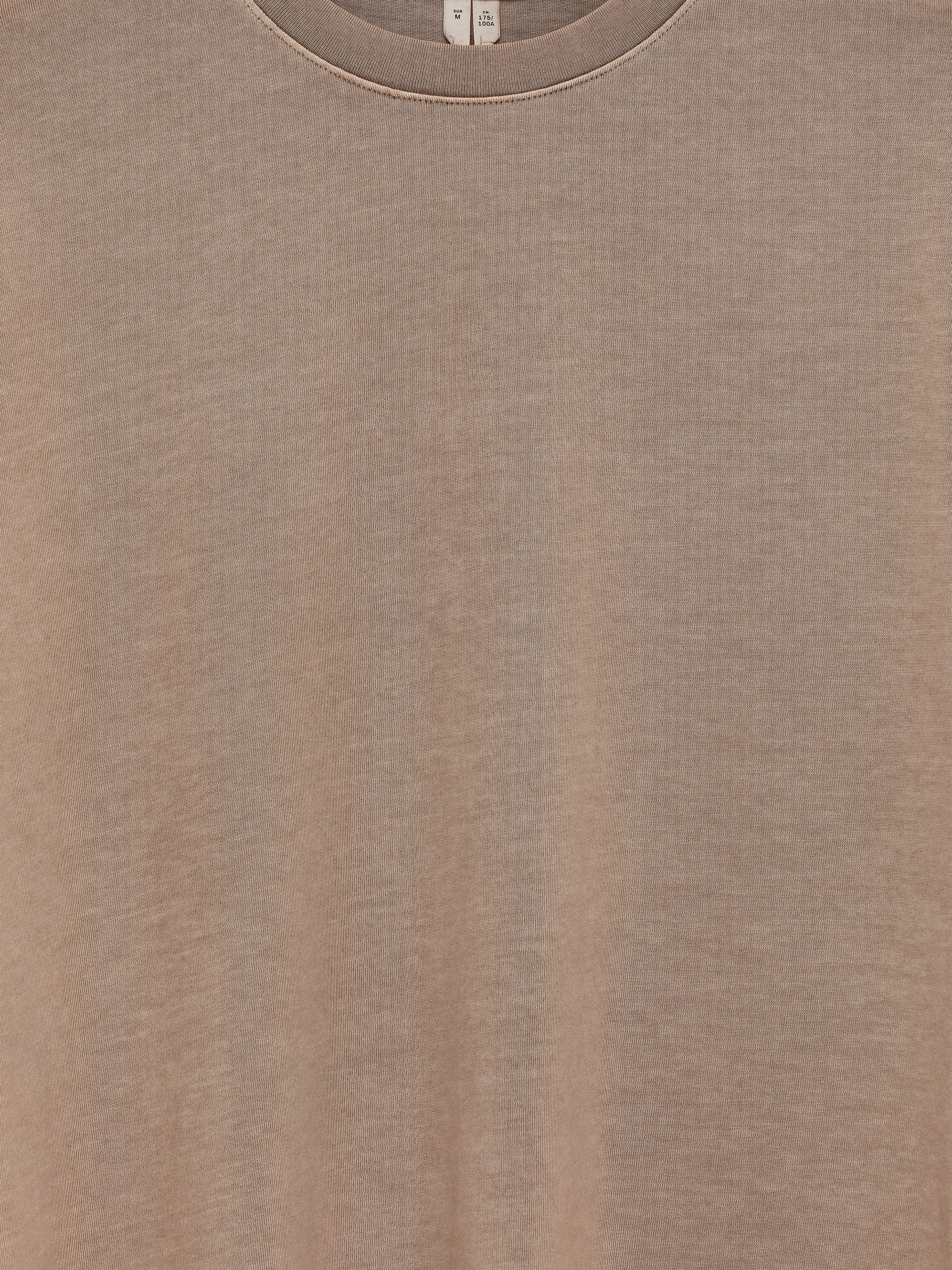 Agrandir l'image: Un T-shirt à manches longues présente sa vue de face. Il est confectionné dans un tissu en coton brun clair chiné et présente un col rond classique avec une bordure côtelée. Les étiquettes du produit sont visibles à l'intérieur de l'encolure.