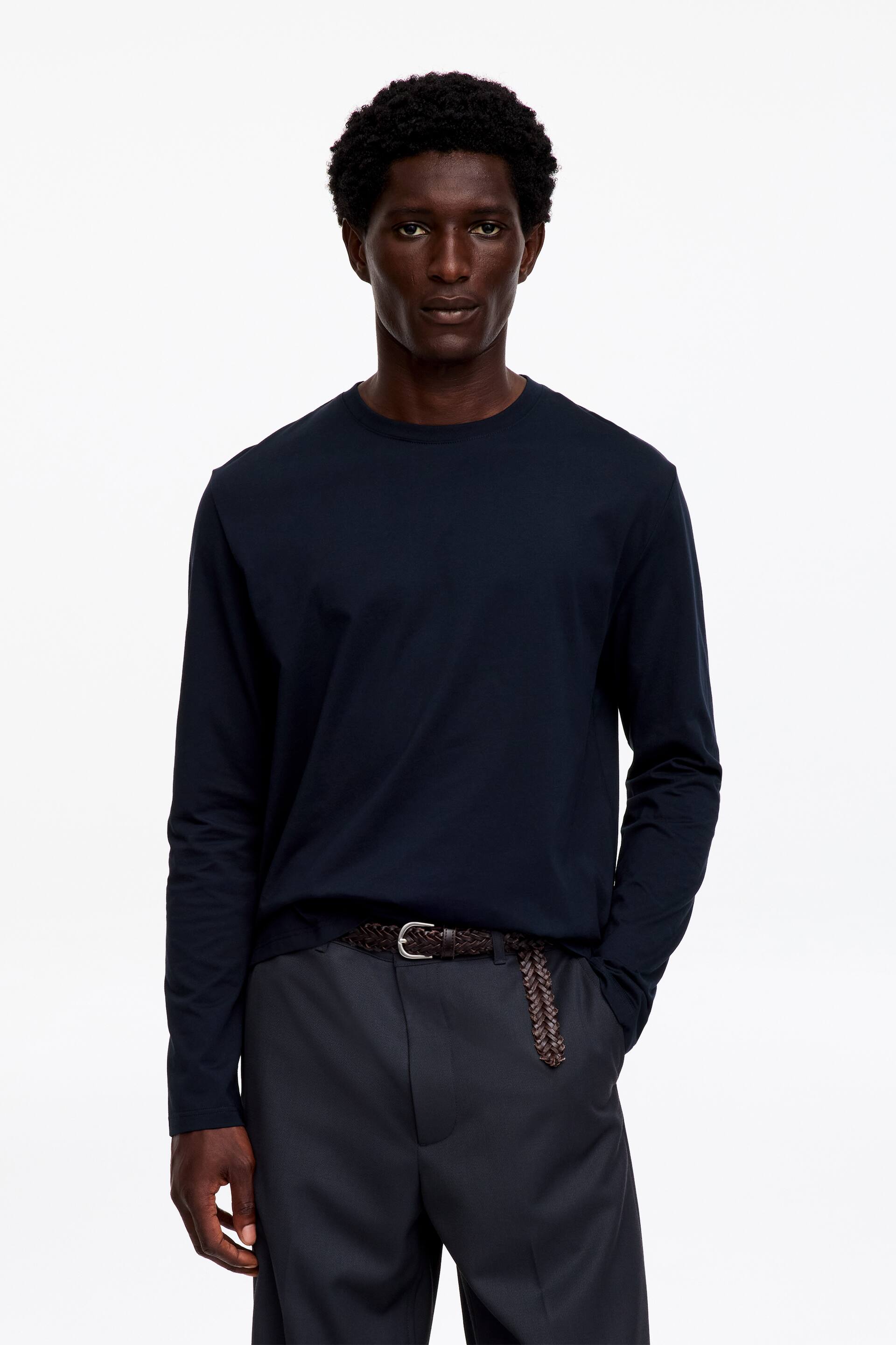 Ver imagen más grande: Una camiseta de manga larga azul oscuro presenta cuello redondo y una textura suave. Se lleva por dentro, mostrando una silueta entallada.