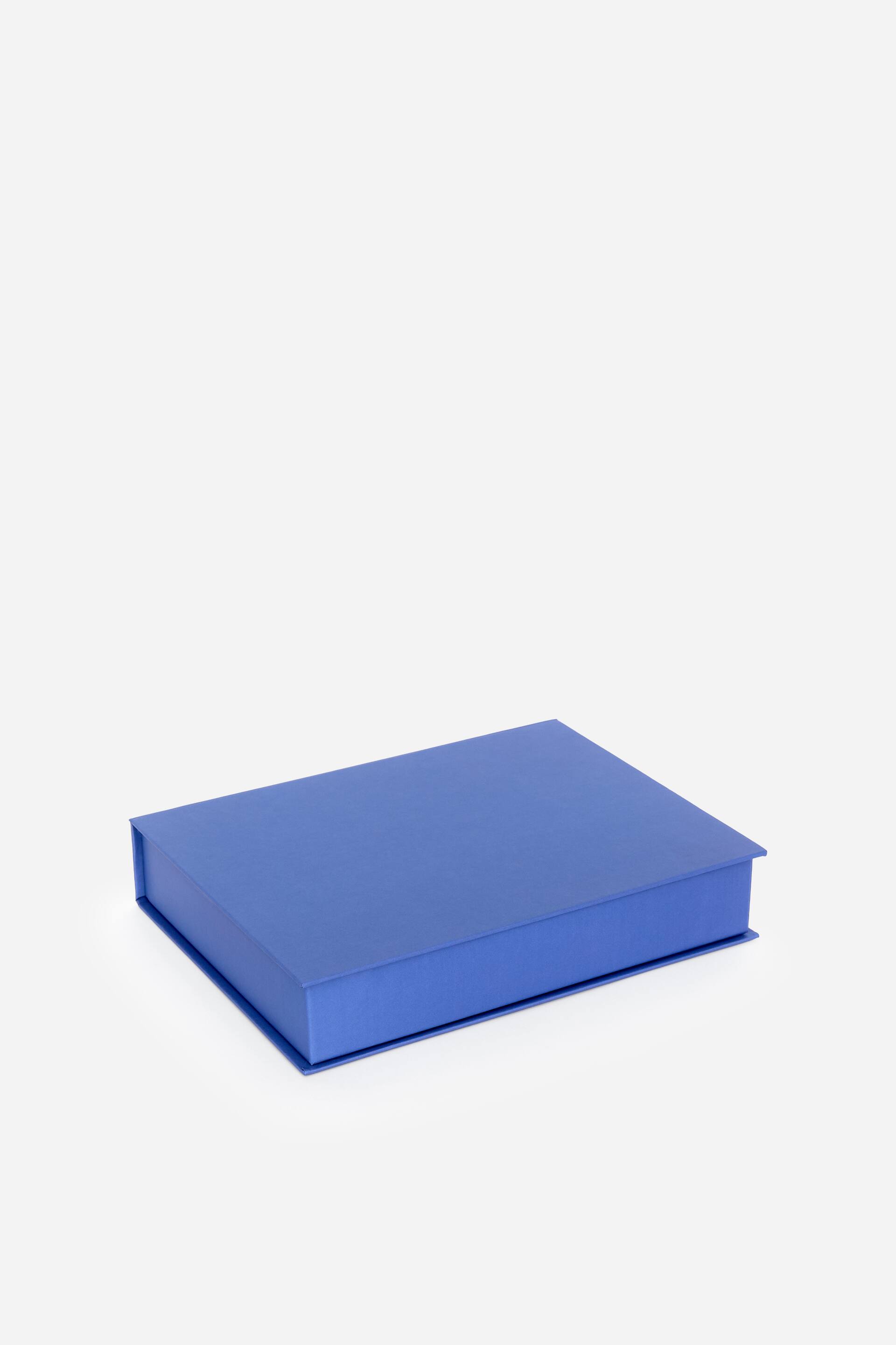 Größeres Bild anzeigen: Eine rechteckige blaue Schachtel wird präsentiert, leicht von oben geneigt, wodurch ihre Oberseite und zwei Seitenflächen sichtbar werden. Sie zeichnet sich durch eine glatte, matte Oberfläche aus, mit einem Deckel, der den Boden abdeckt und leicht über die Seiten hinausragt.