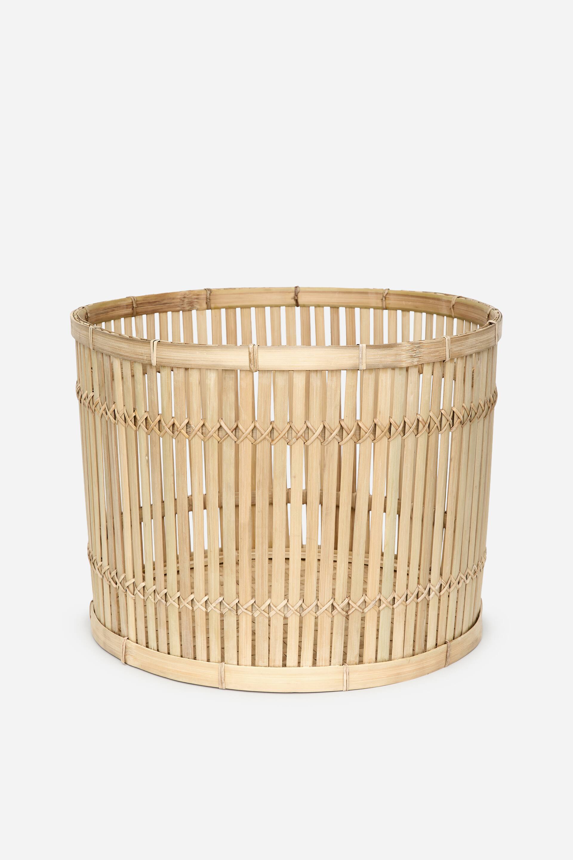 Se større billede: En rund, åben-top bambuskurv i en naturlig lys farve præsenteres. Vertikale bambusstrimler danner siderne, som sikres af horisontale bånd og et krydsflettet mønster.