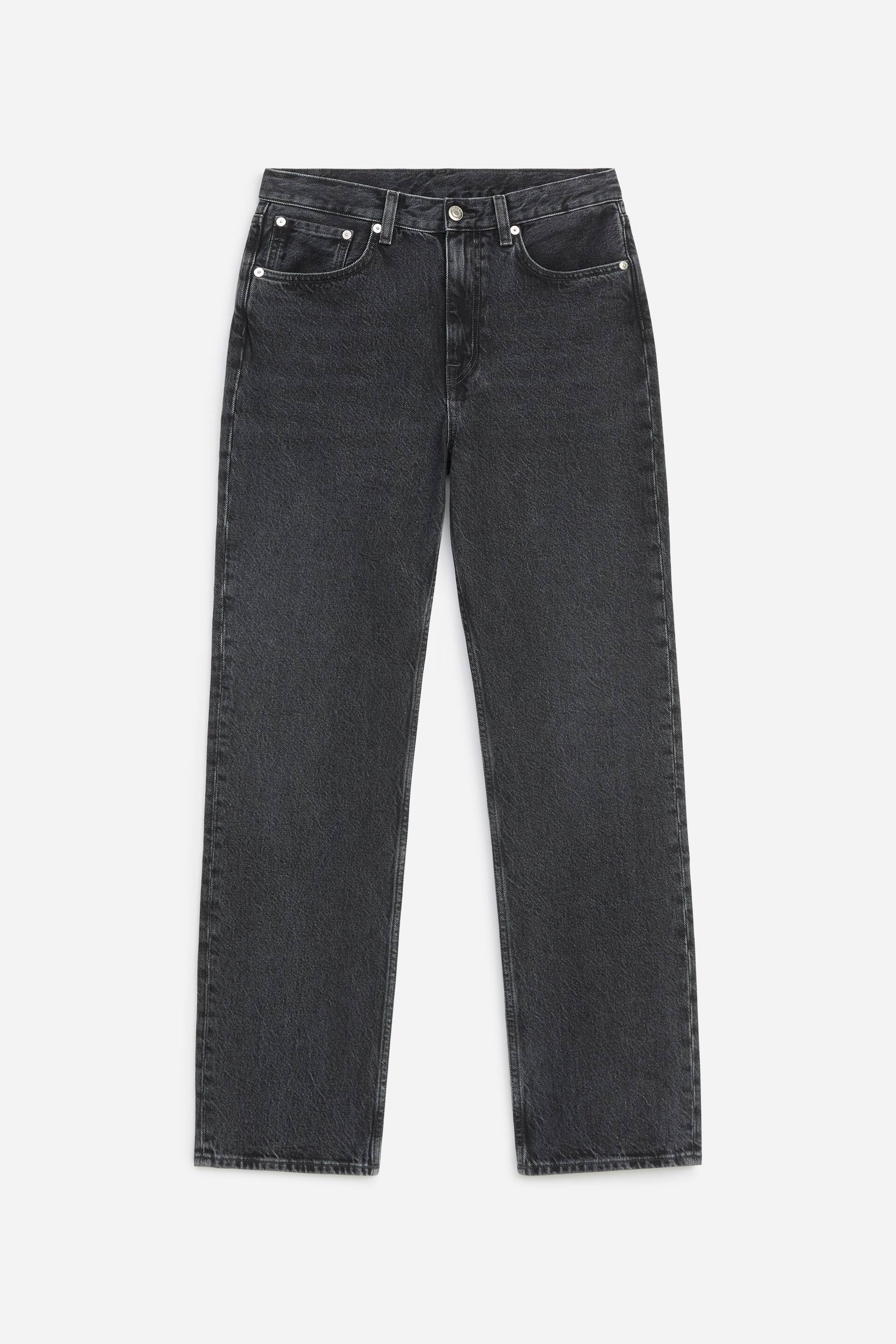 Ver imagem maior: É mostrado um par de jeans pretos desbotados de perna direita, visto de frente, com cintura de altura média, estilo clássico de cinco bolsos e rebites metálicos em tom prateado.
