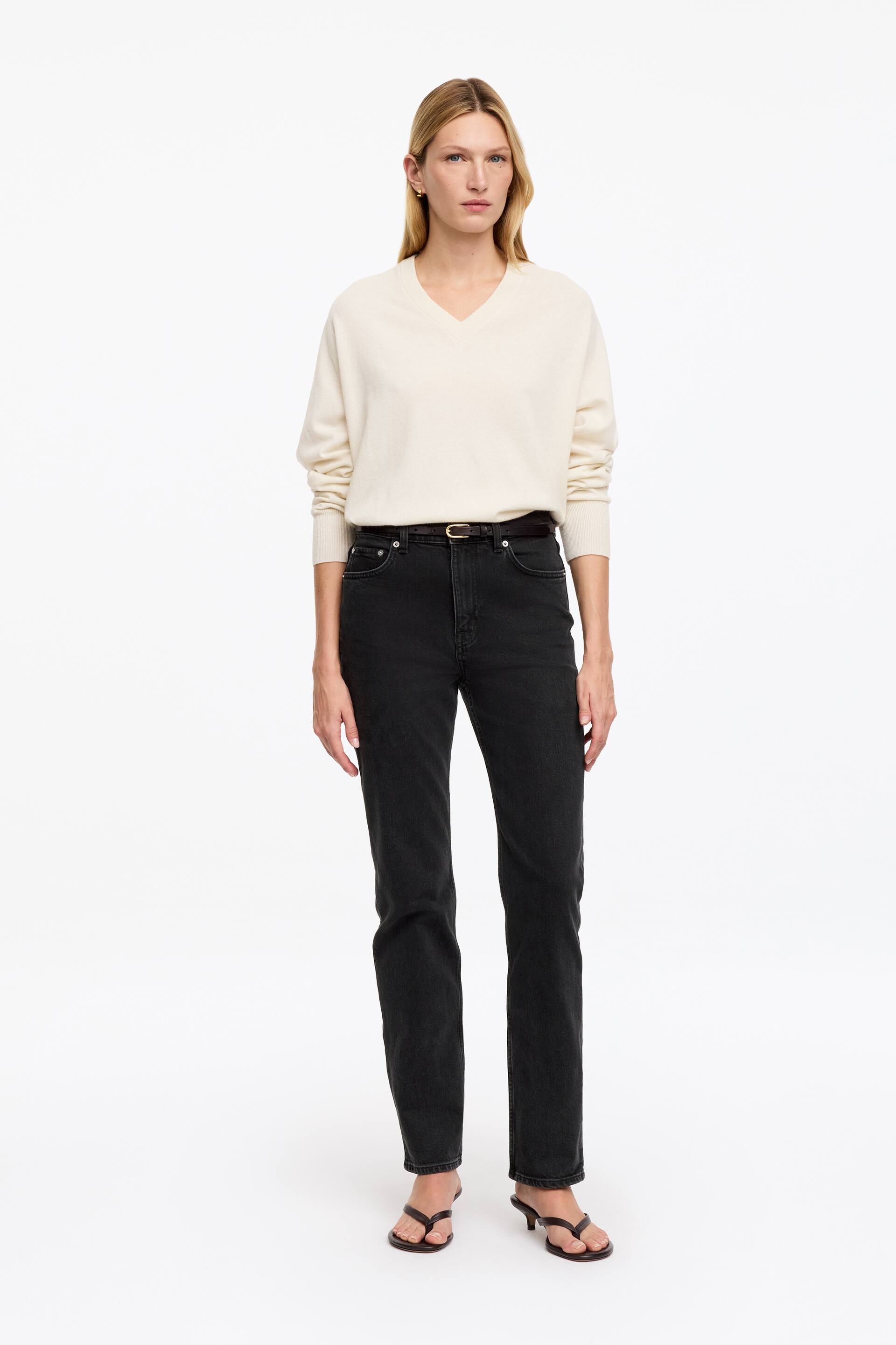 Visualizza immagine più grande: I jeans JADE, in un lavaggio scuro, sono indossati dalla modella e presentano vita media, vestibilità slim e gamba affusolata a tutta lunghezza. Un maglione chiaro è infilato nei jeans, mentre una cintura scura è passata attraverso i passanti.