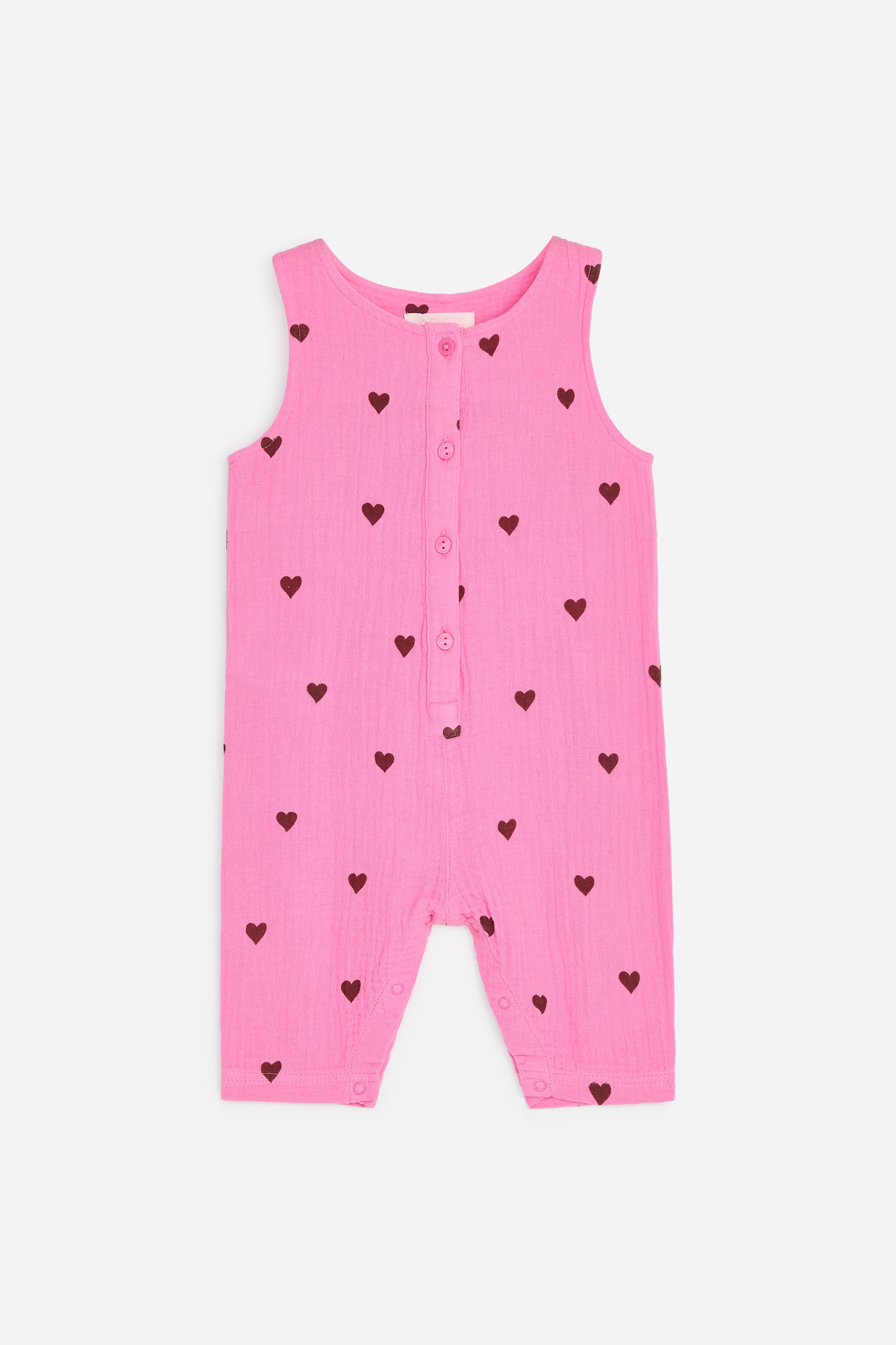 Größeres Bild ansehen: Ein ärmelloser rosa Baby-Strampler zeigt seine Vorderseite, mit einer gekräuselten Textur und einem durchgehenden dunkelroten Herzmuster. Er ist mit einer durchgehenden Knopfleiste an der Vorderseite und Druckknöpfen im Schritt gestaltet.