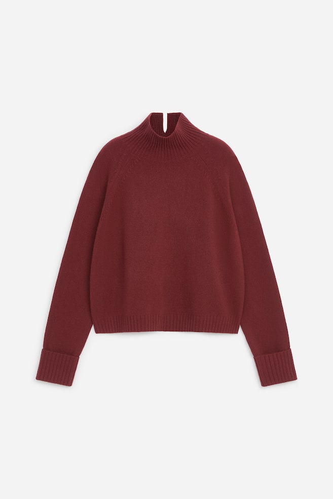 Acest pulover tricotat bordo, prezentat din faÈÄ, are guler rulat cu structurÄ ribatÄ Èi o micÄ fantÄ la spate, mâneci raglan Èi manÈete ribate pliate. Articolul are o croialÄ clasicÄ Èi tiv ribat. - 1