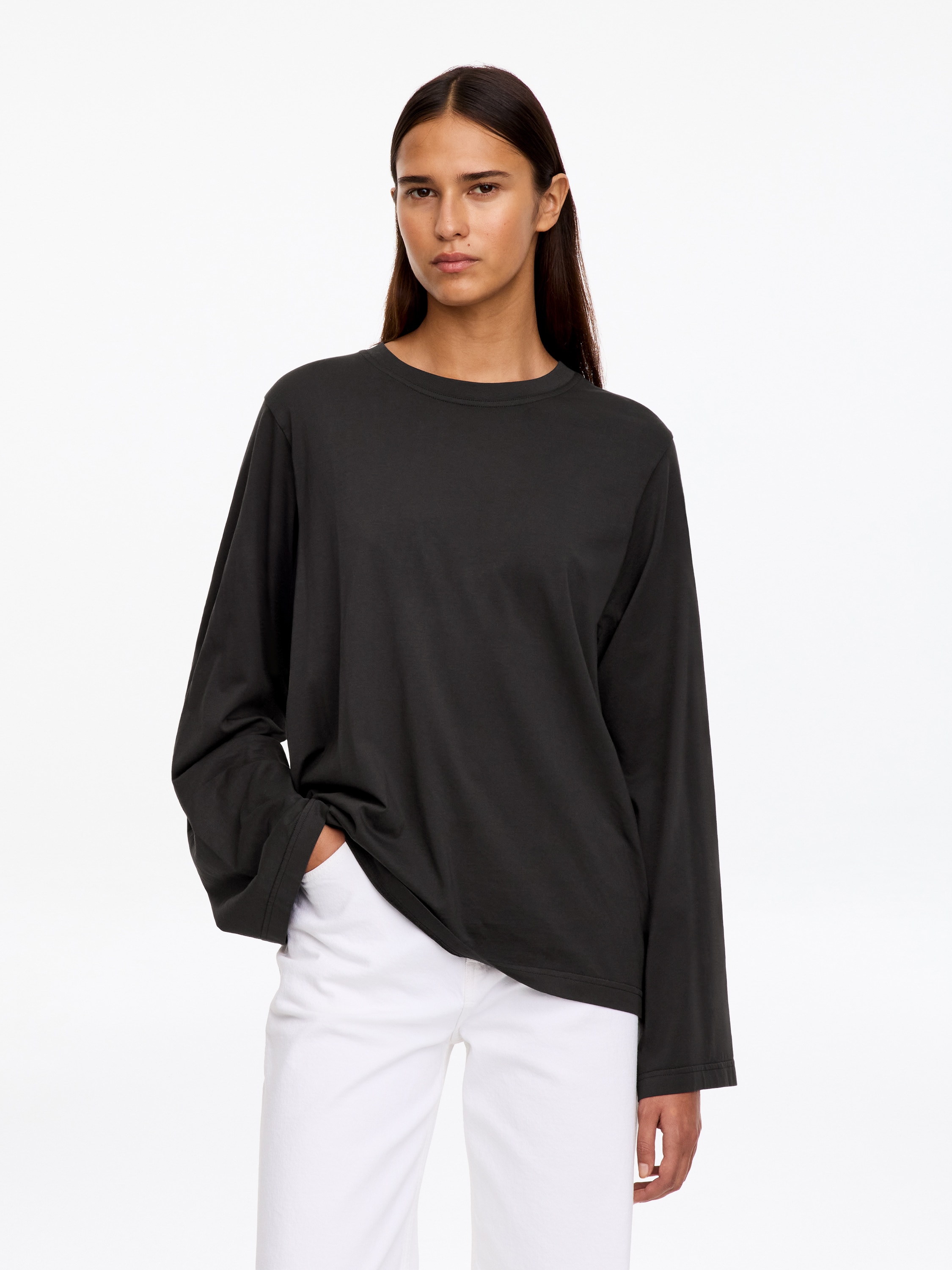 Un tricou cu mÃ¢necÄ lungÄ, Ã®n gri Ã®nchis estompat, este aÈezat Ã®ntins, prezentÃ¢nd partea din faÈÄ Èi o croialÄ lejerÄ, relaxatÄ. Articolul vestimentar are un decolteu rotund cu nervuri, mÃ¢neci lungi Èi largi, cu manÈete tivite, Èi un tiv drept.