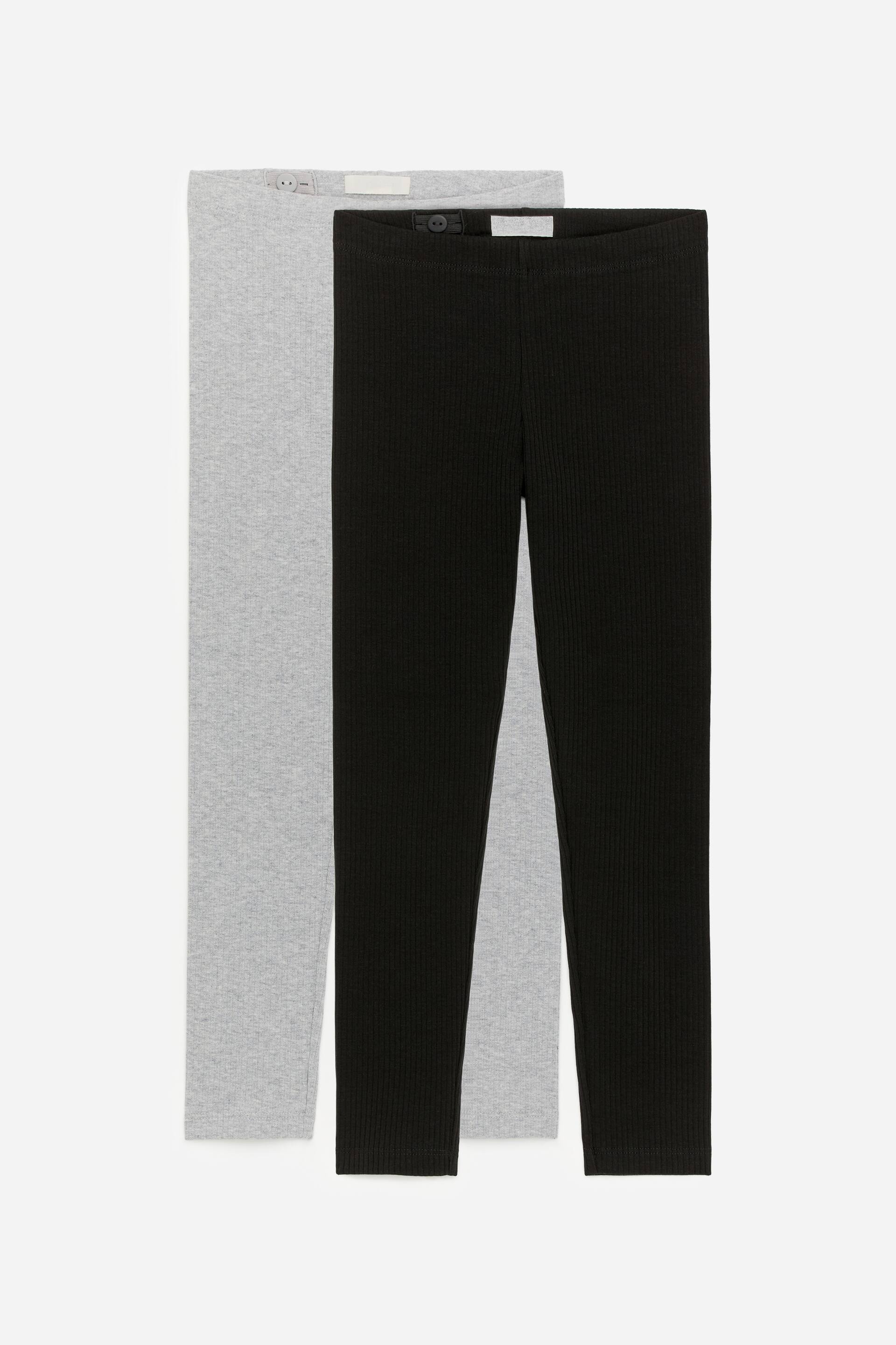 Ingrandisci l'immagine: Due paia di leggings a coste sono distesi in piano, mostrando la parte anteriore. Un paio è grigio chiaro e l'altro è nero, entrambi con una fascia elastica in vita con dettagli regolabili visibili.