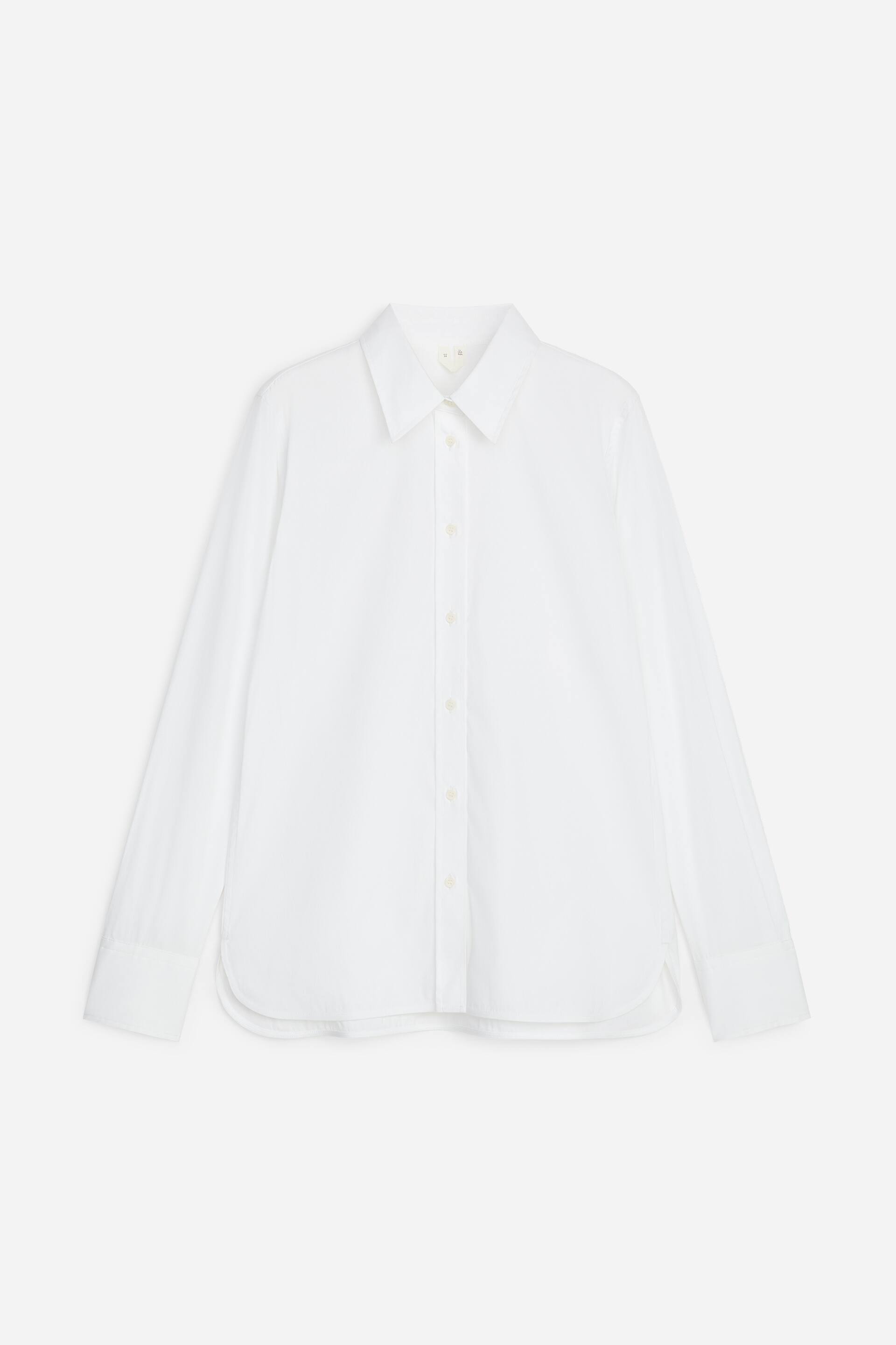 View larger image: A white shirt is displayed from the front, showcasing a pointed collar, a full button placket with light-coloured buttons, long sleeves with single-button cuffs, a rounded hemline, and a relaxed fit.