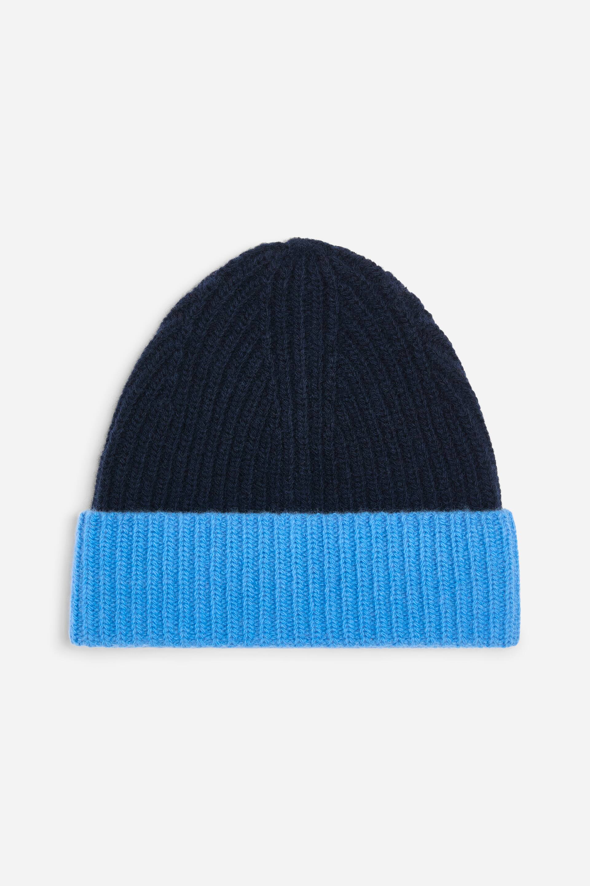 Größeres Bild anzeigen: Eine zweifarbige, gerippte Strickmütze ist von vorne zu sehen, mit einer dunkelblauen Krone und einem leuchtend blauen, umgeschlagenen Bund. Sie zeigt eine grob gestrickte Verarbeitung.