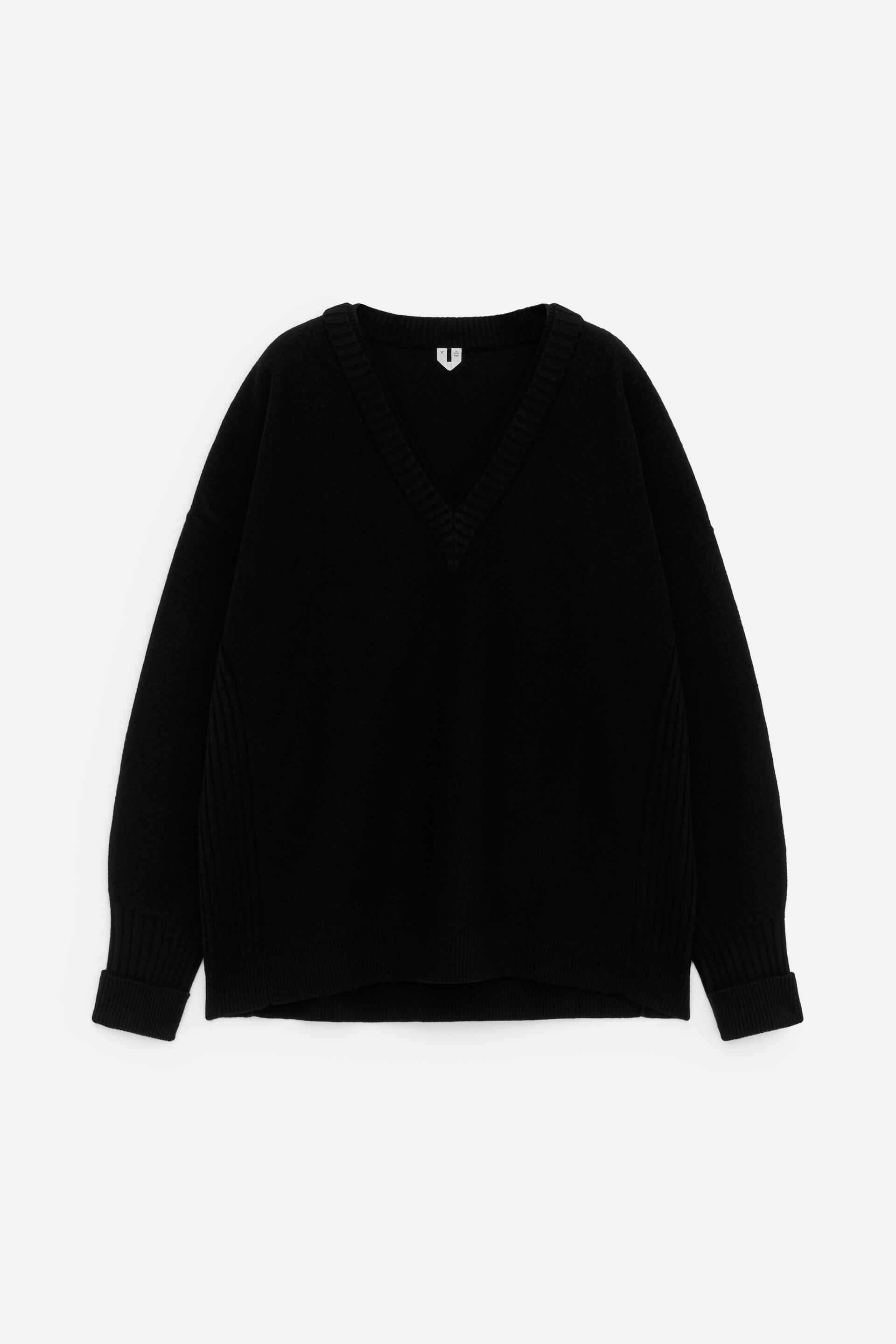 Größeres Bild ansehen: Ein schwarzer V-Ausschnitt-Pullover wird von vorne präsentiert, mit einem gerippten V-Ausschnitt und hochgekrempelten gerippten Bündchen. Der locker sitzende Pullover zeigt außerdem vertikale gerippte Seitenpaneele und einen gerippten Saum.