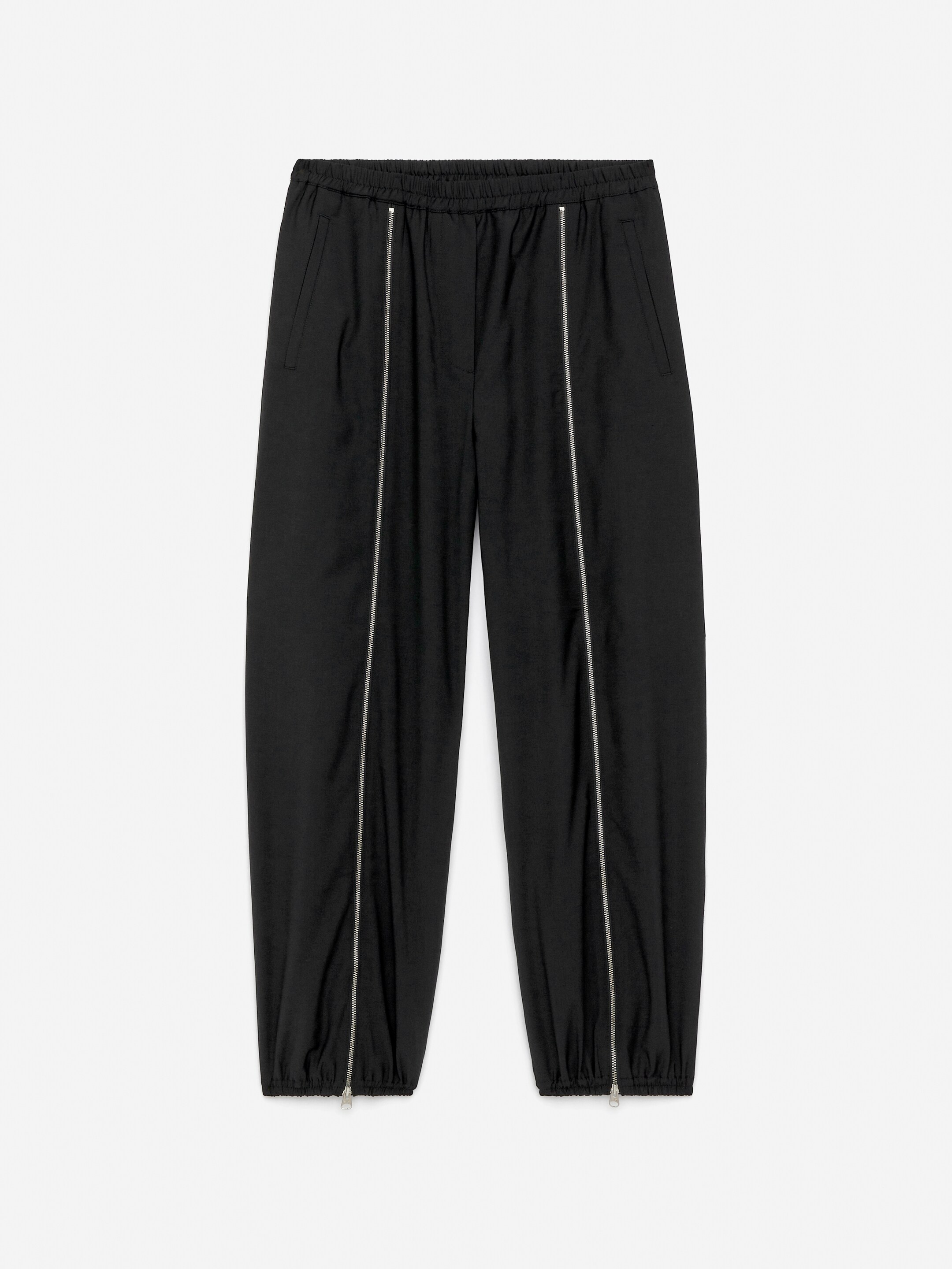 View larger image: Black sweatpants are presented from the front, featuring an elasticated waist and cuffs. Vertical silver-toned zip detailing is running along each leg, complementing the tapered silhouette and visible welt side pockets.
