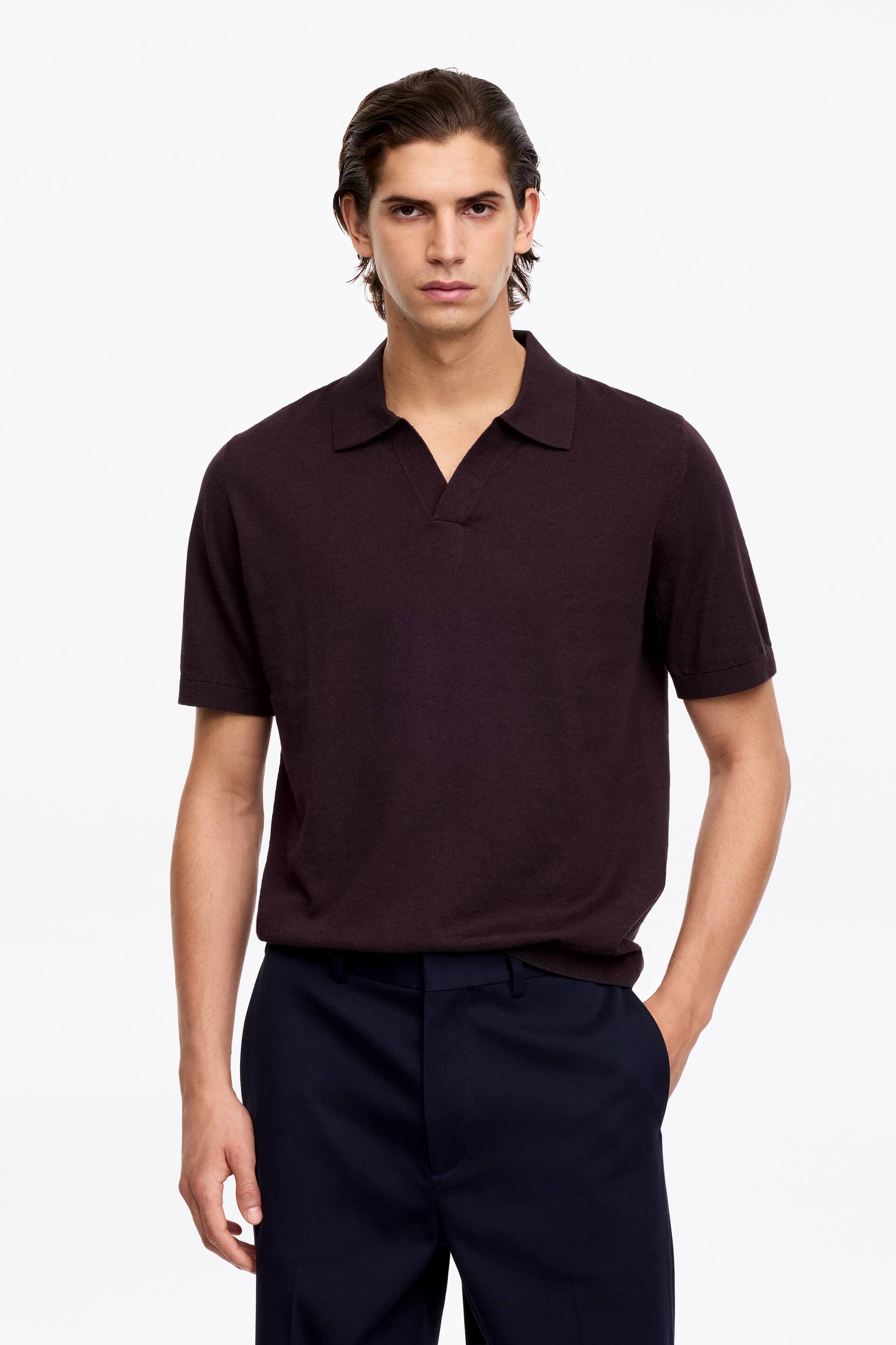 Größeres Bild ansehen: Ein dunkelviolettes Polohemd mit kurzen Ärmeln, das einen Spread-Kragen mit offenem V-Ausschnitt aufweist, präsentiert eine feine Stricktextur und einen geraden Saum.