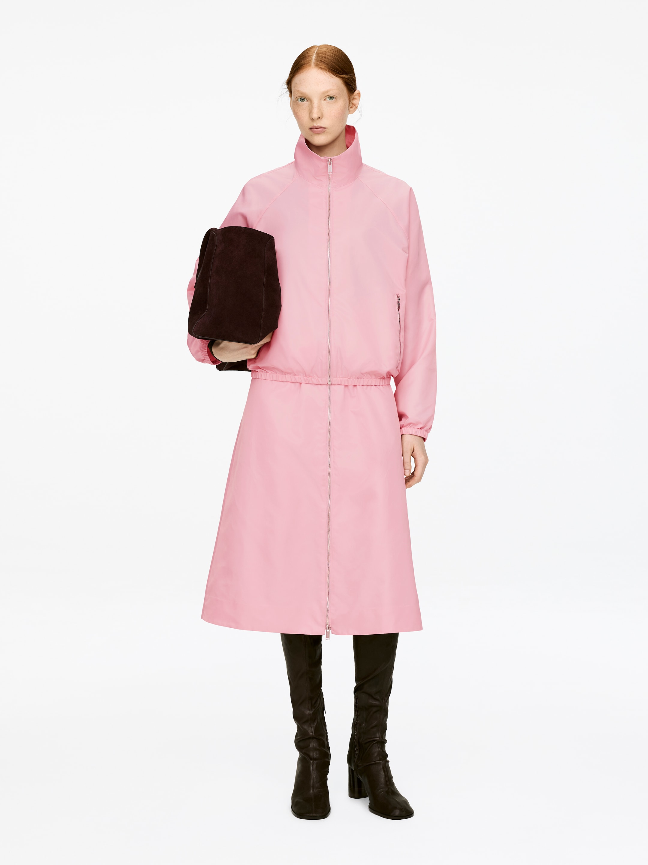 View larger image: A pink midi skirt, featuring a two-way zip at the front and an elasticated waist, is being worn by the model.